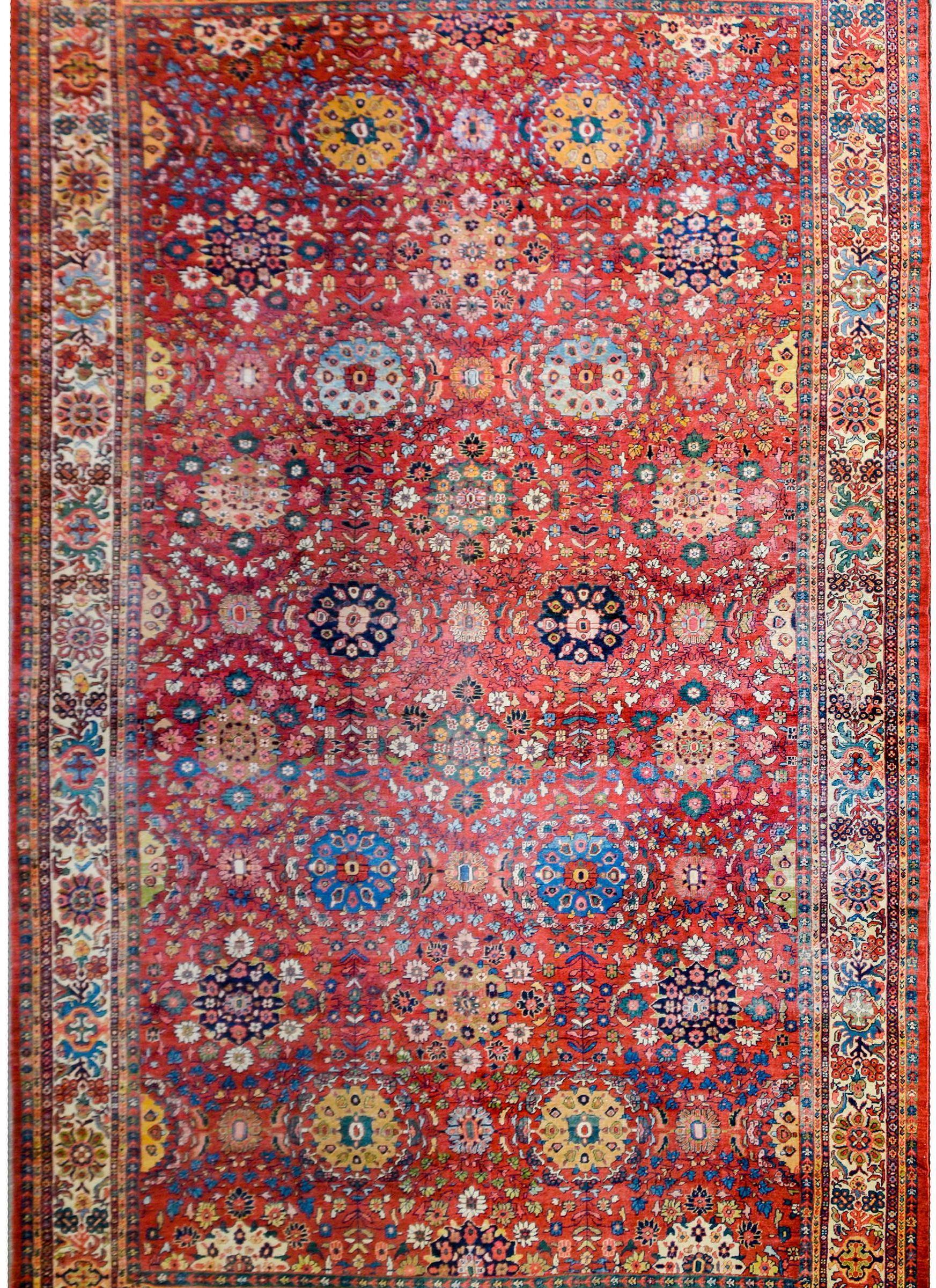 An unbelievable circa 1900s antique Persian Sultanabad rug with an exceptional overall pattern containing multiple large-scale multicolored flower medallions amidst a tightly woven pattern of scrolling vines with leaves and flowers on a crimson