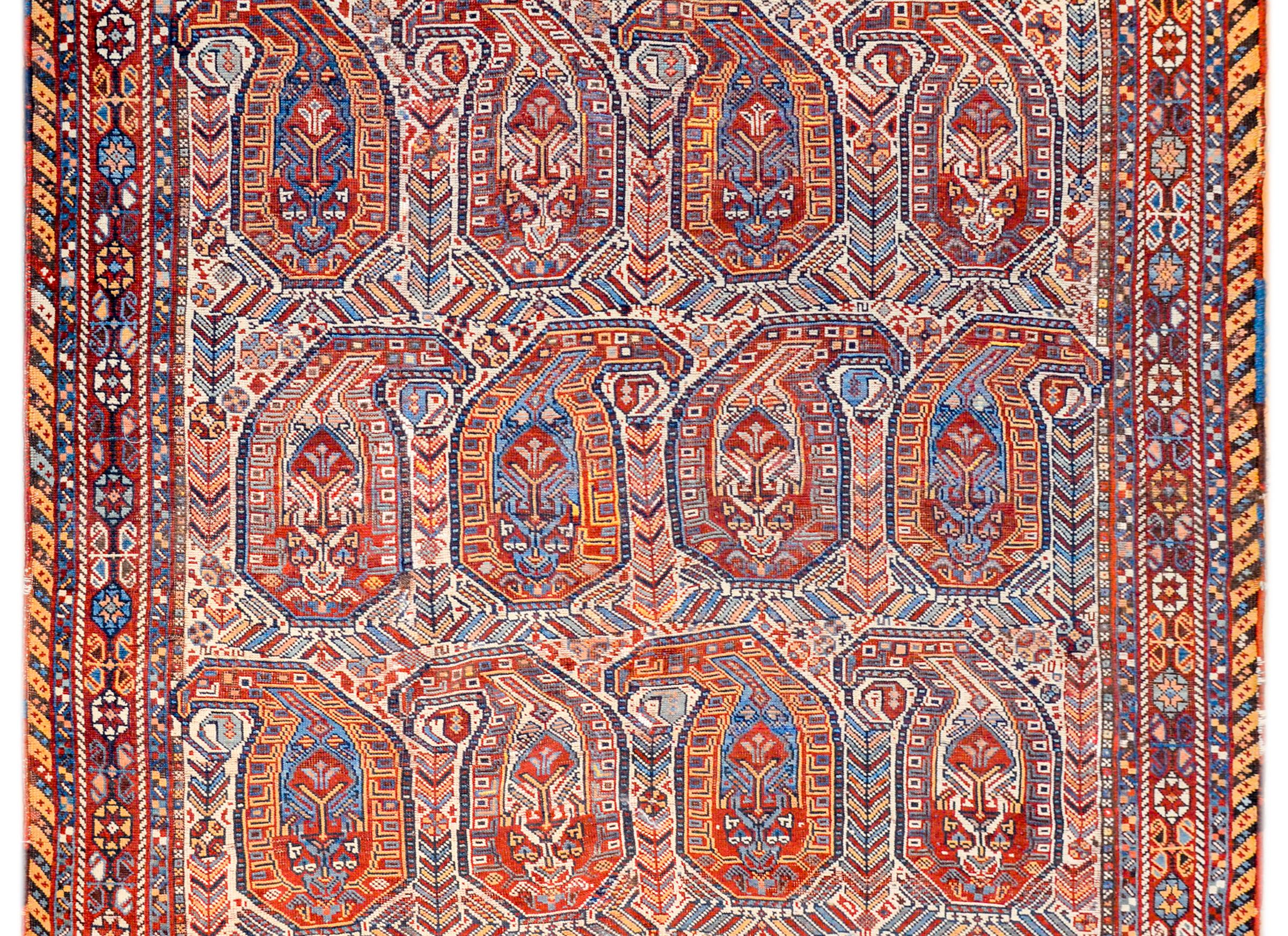 An unbelievable early 20th century Persian Gashgaei rug with an all-over large scale paisley pattern woven in crimson, gold, indigo, coral, black, and white colored vegetable dyed wool. The border is outstanding, with a tightly woven pattern