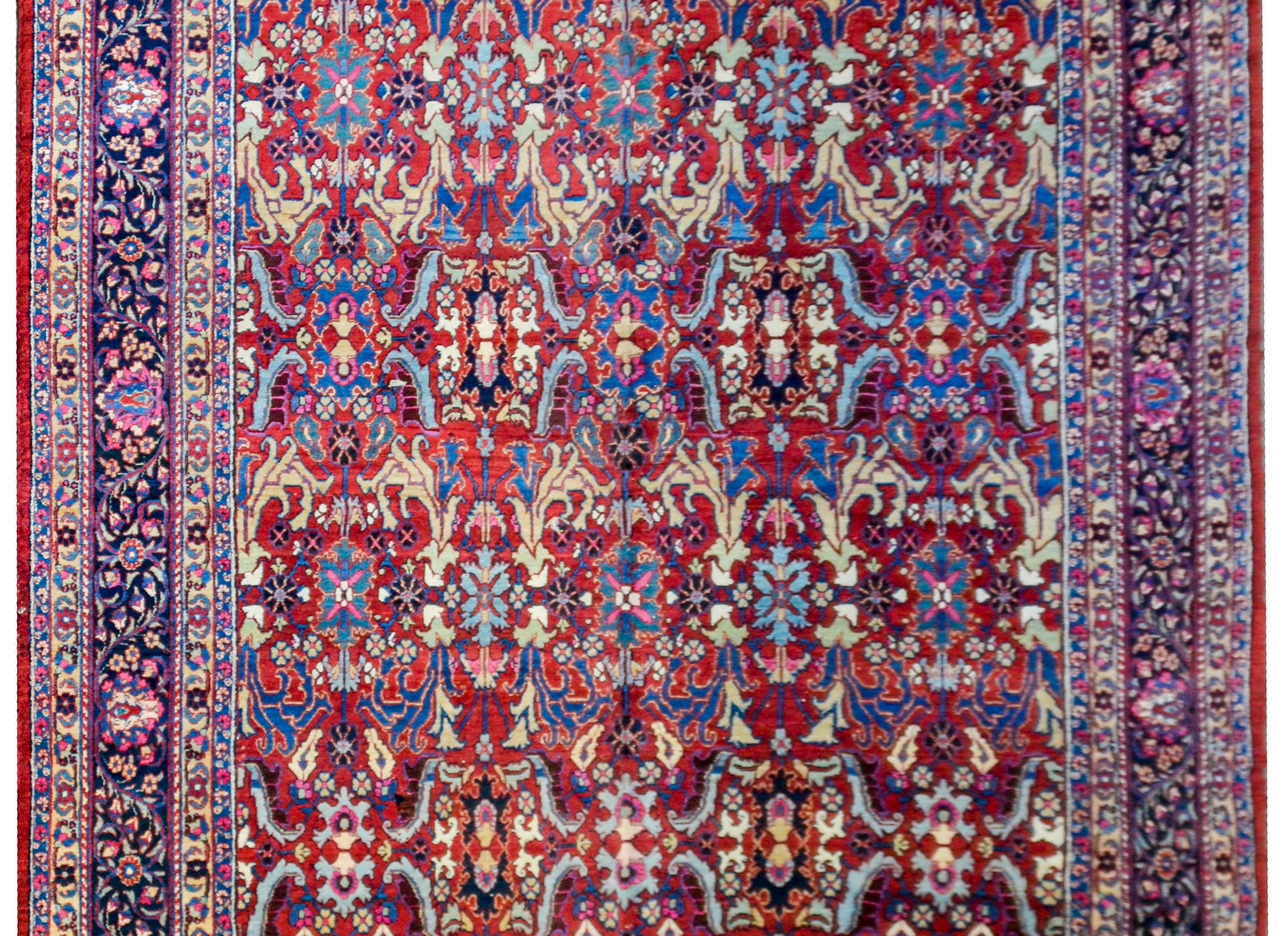An unbelievable early 20th century Persian Heriz rug with an incredible all-over mirrored floral and leaf trellis pattern woven in light and dark indigo, yellow, and pink on a brilliant crimson background. The border is wonderful with a wide central