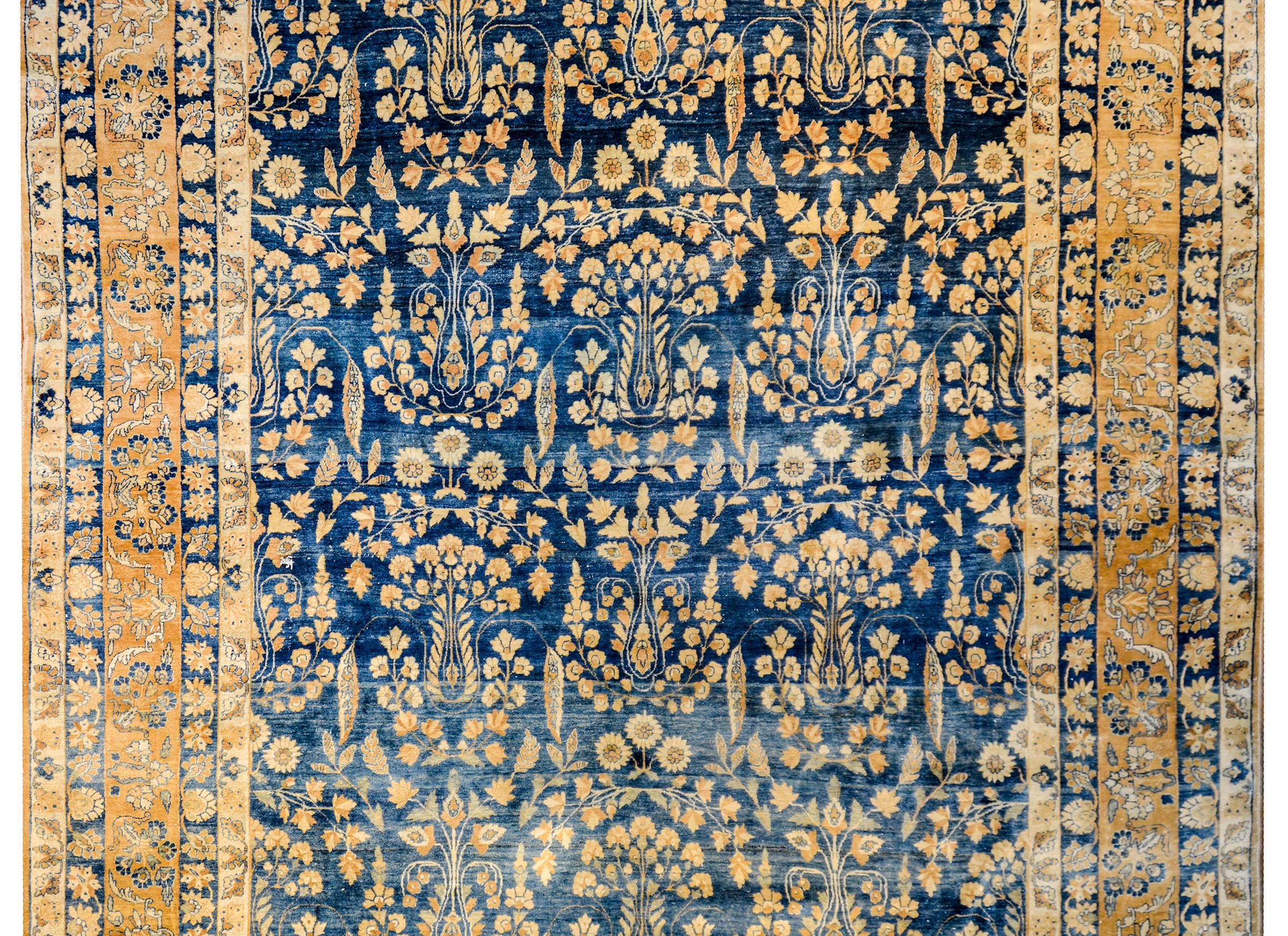 An unbelievable and extraordinary early 20th century Persian Lavar Kirman rug with a brilliant tree-of-life pattern woven in natural creams and champagne colored wool, on a bold abrash indigo background. The border is equally beautiful with multiple