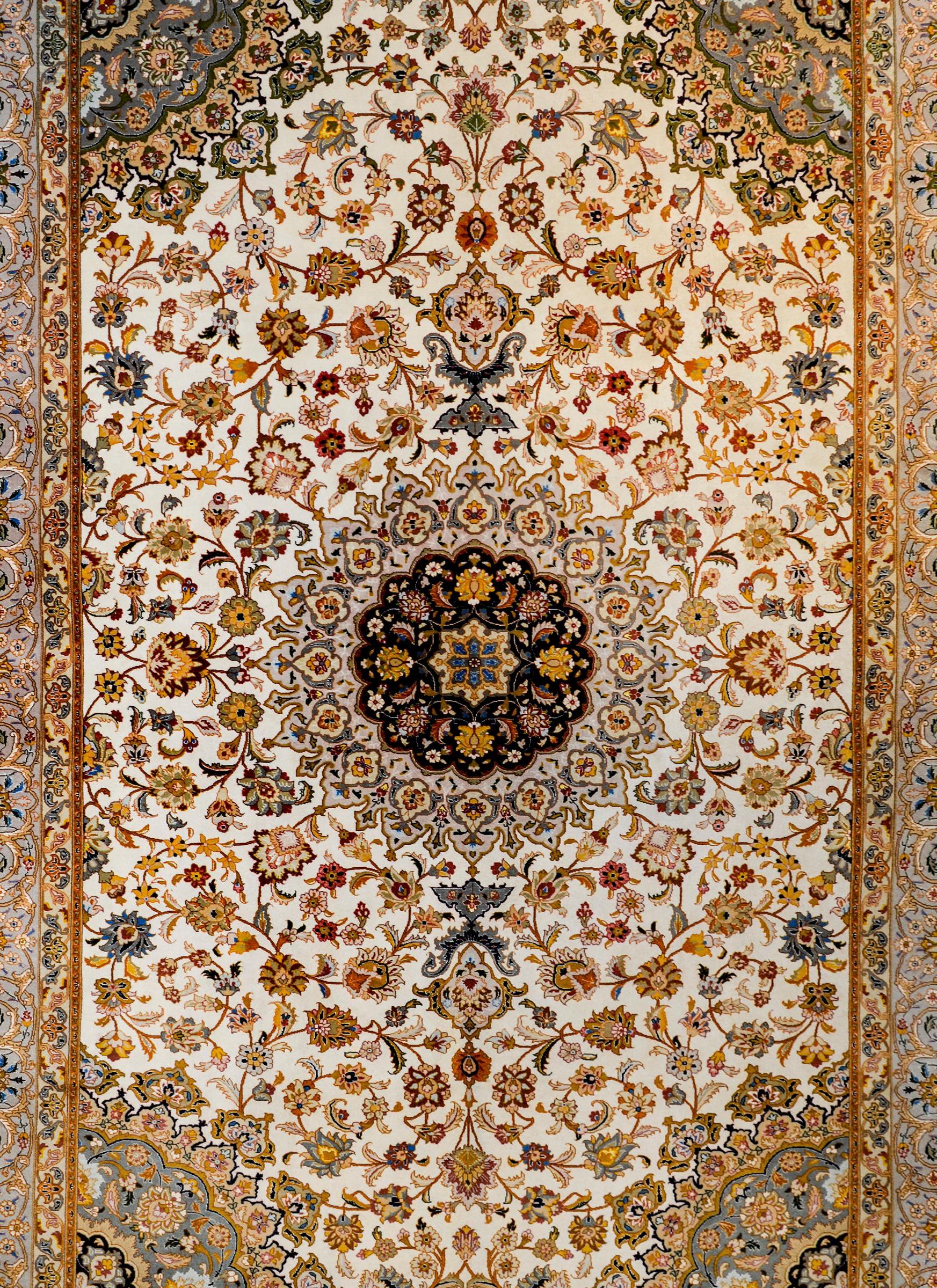 An extraordinary vintage Persian silk and wool Tabriz rug with a skillfully and precisely rendered large-scale floral and vine pattern. The flowers are woven in crimson, orange, gold, indigo, green, and white vegetable dyed silk and wool, on a white