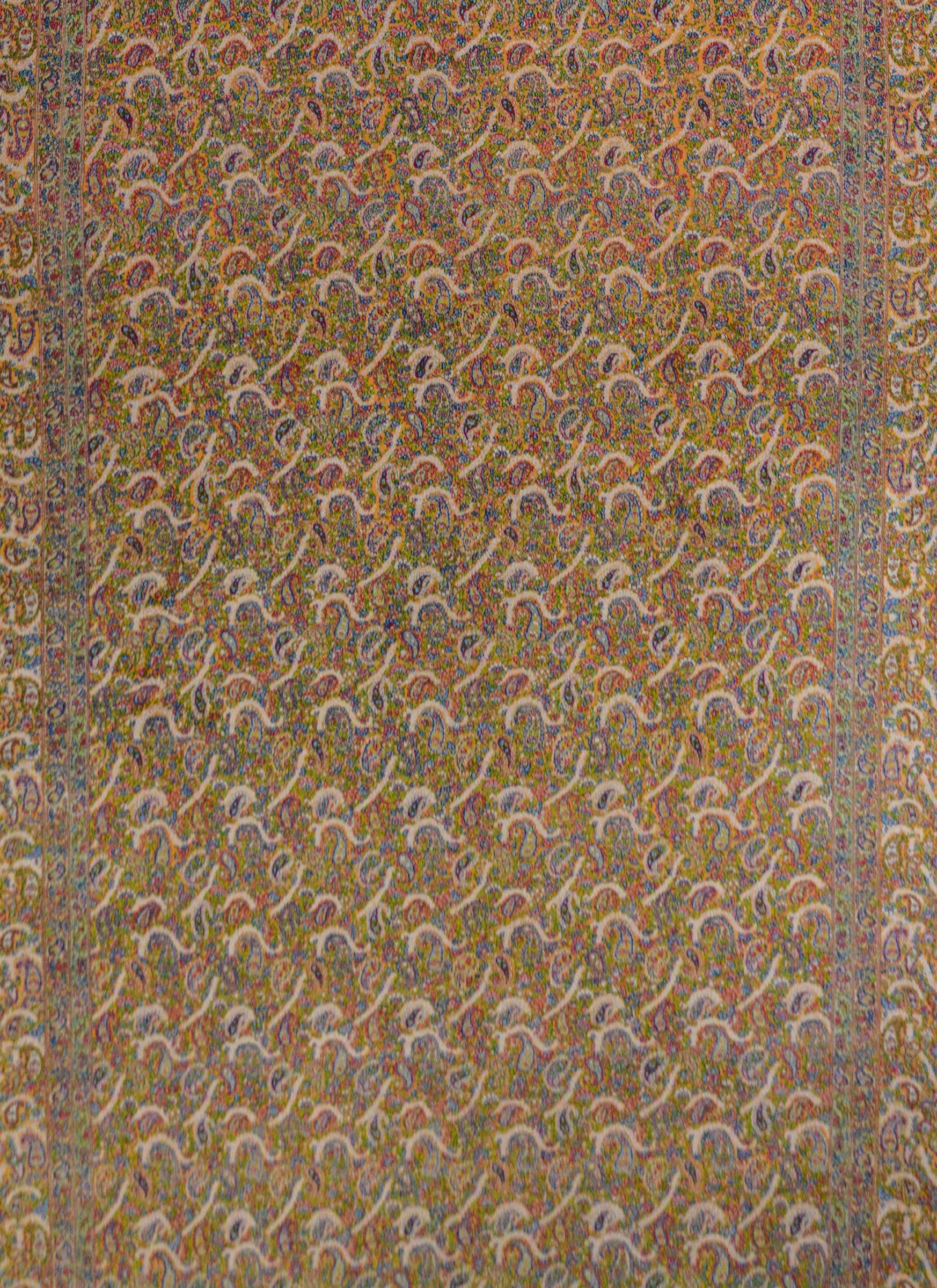 Ein unglaublicher persischer Kirman-Teppich aus der Mitte des 20. Jahrhunderts mit einem intensiv gewebten Paisley- und Blumenmuster in unzähligen Farben auf einem glänzenden Goldgrund, umgeben von einer Bordüre mit demselben Muster wie das Feld.