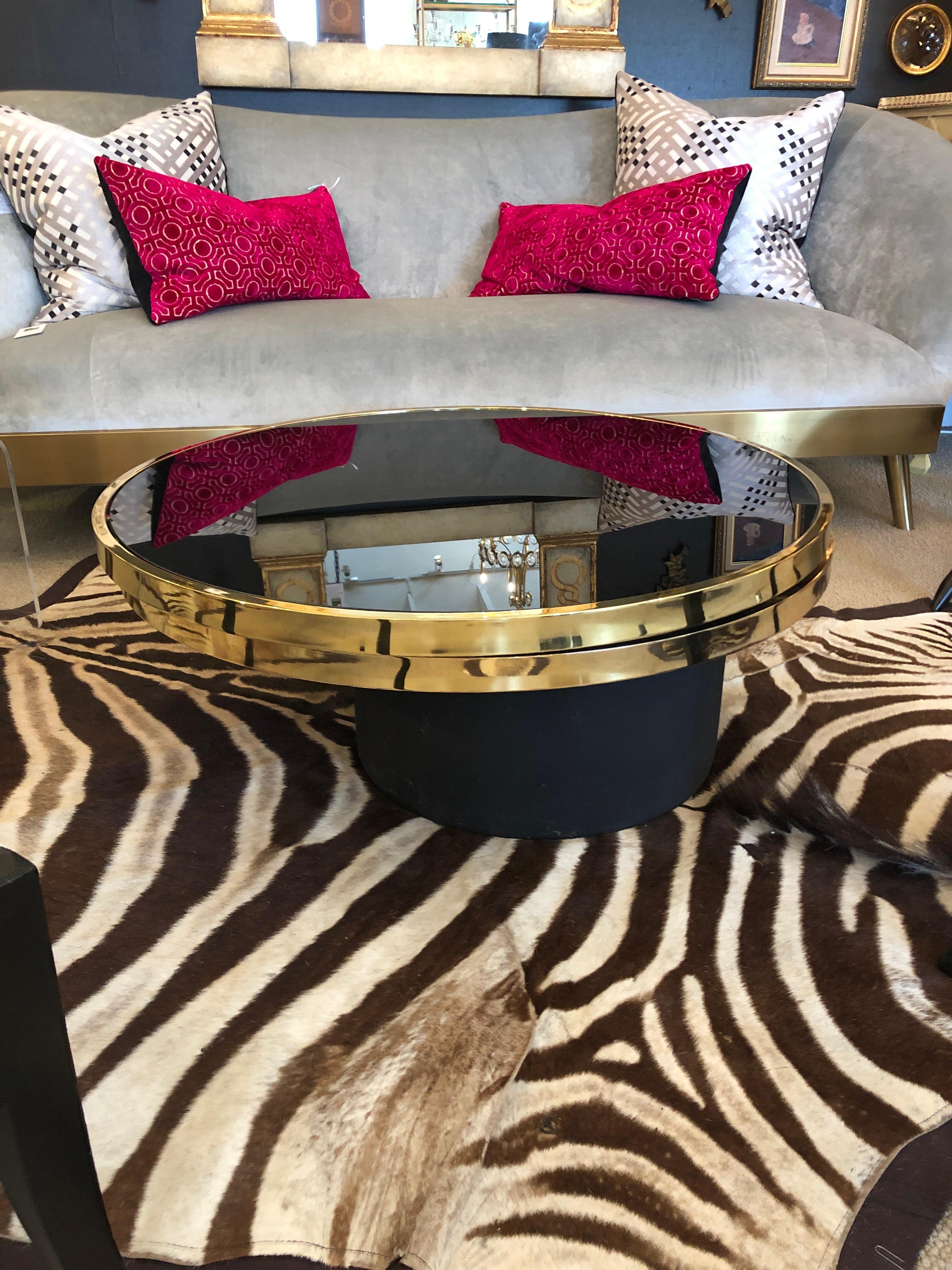 Incredibly chic brass and black glass swivel cocktail table by the Design Institute of America. The glass and brass glisten in the light and the glass is free of any chips or major scratches. The swivel mechanism works flawlessly. Table top rotates