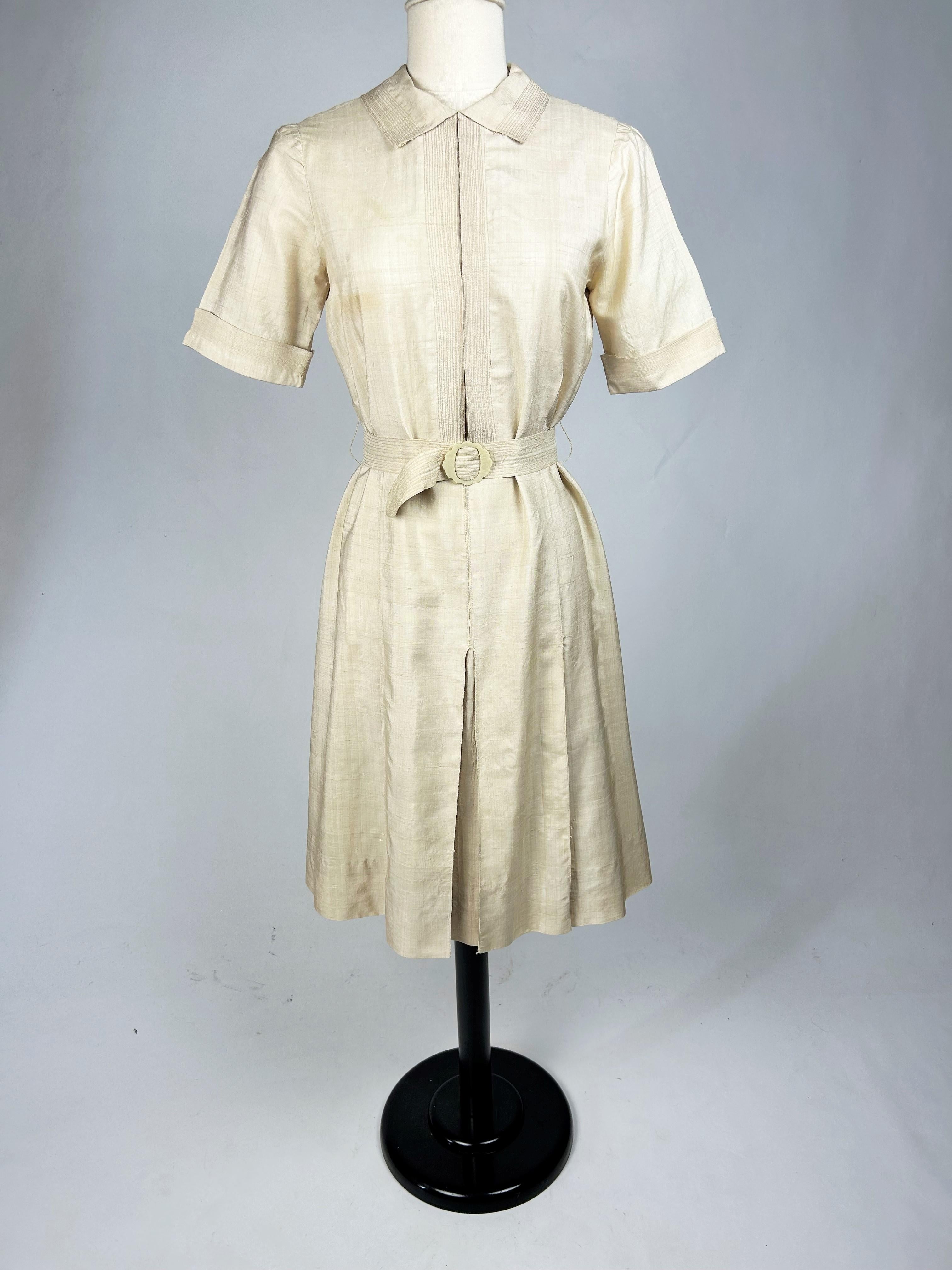 Circa 1930-1940

France

Elegant summer dress in unbleached raw silk from the 1930s-1940s, inspired by the sober, relaxed cuts of Mademoiselle Chanel. A straight dress with a small Claudine crew neck, short sleeves and a back zip. Interesting