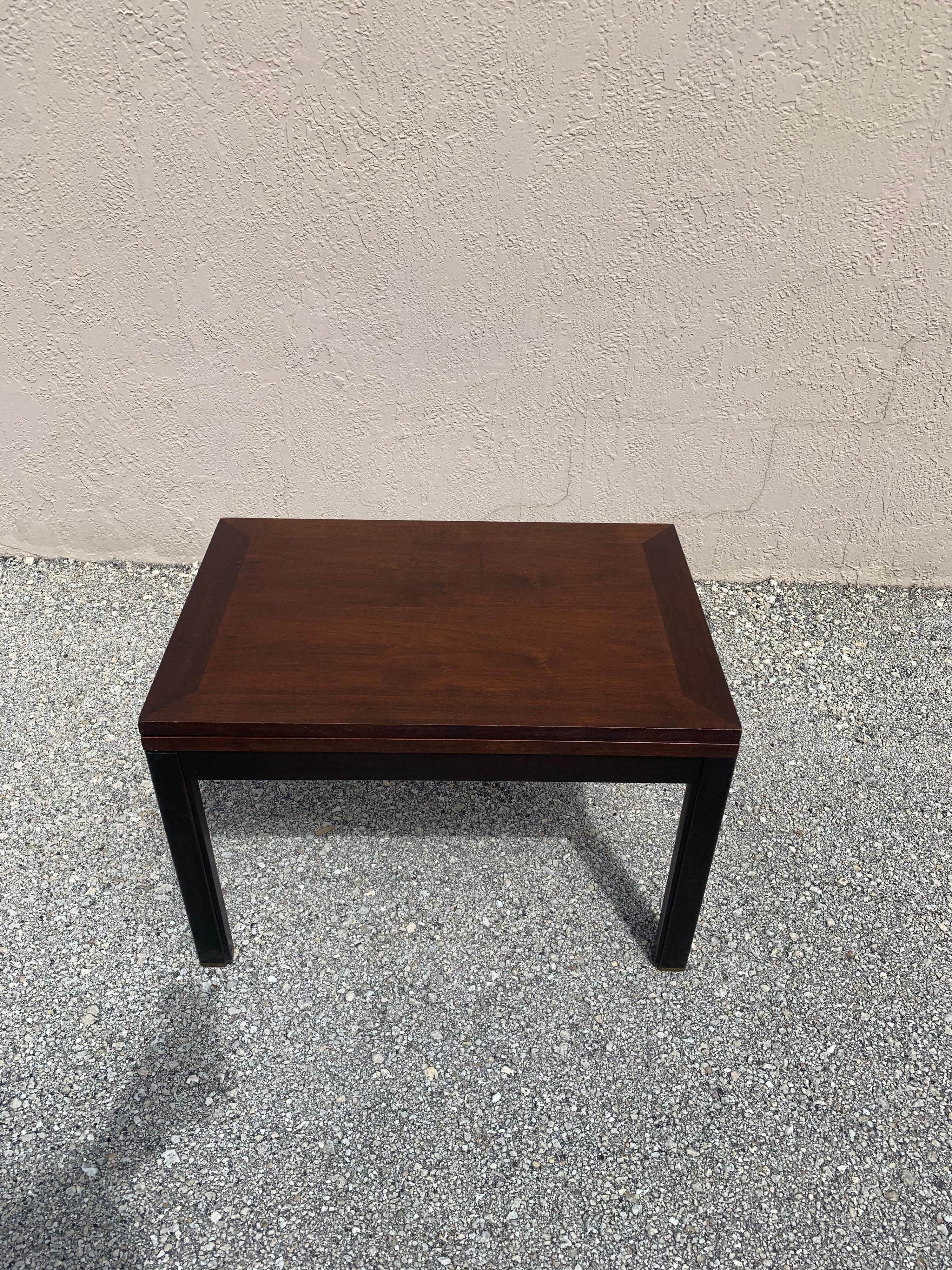 Flip top coffee table designed by Edward Wormley for Dunbar. In a dark espresso finish with brass capped feet. Table top starts at a 27” by 18” surface but with a quick spin and a flip opens up to a 36” by 27” surface. Turning the top exposes a