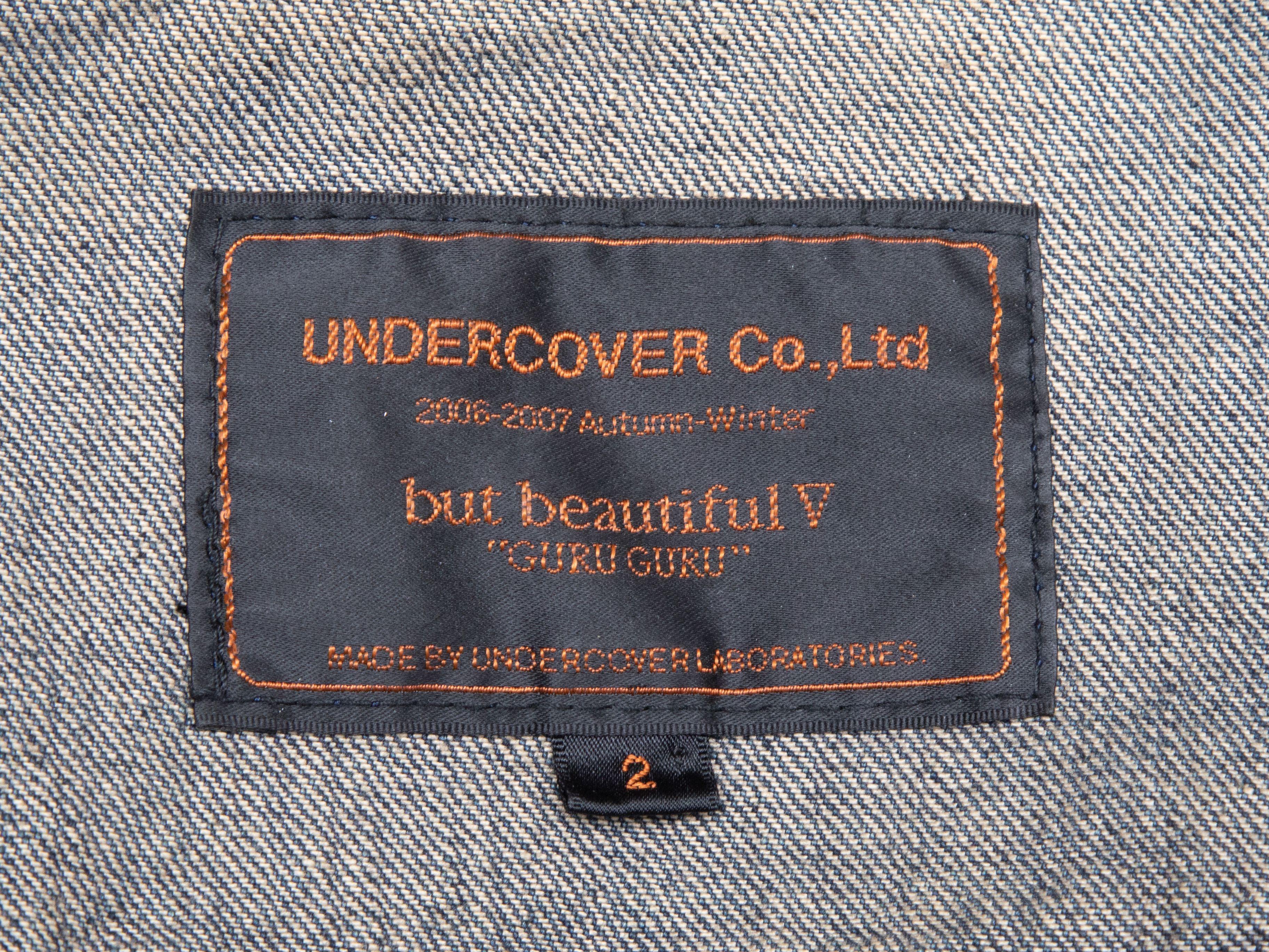 Product Details: Dark wash embroidered denim jacket by Undercover. From the Fall/Winter 2006-2007 Collection. Pointed collar. Dual flap pockets at bust. Apple motif embroidery at back. Zip closure at center front. 36