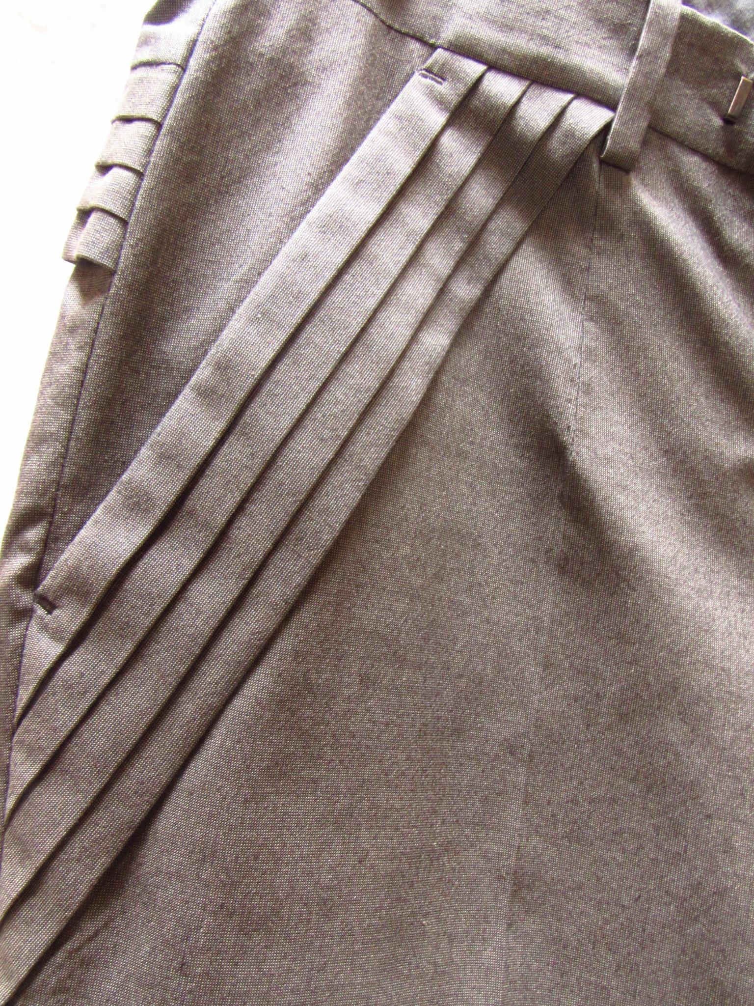 Undercover vous propose un pantalon gris en gabardine de coupe étroite, avec de magnifiques détails de plis le long du bord supérieur des poches latérales obliques et dans le dos.
