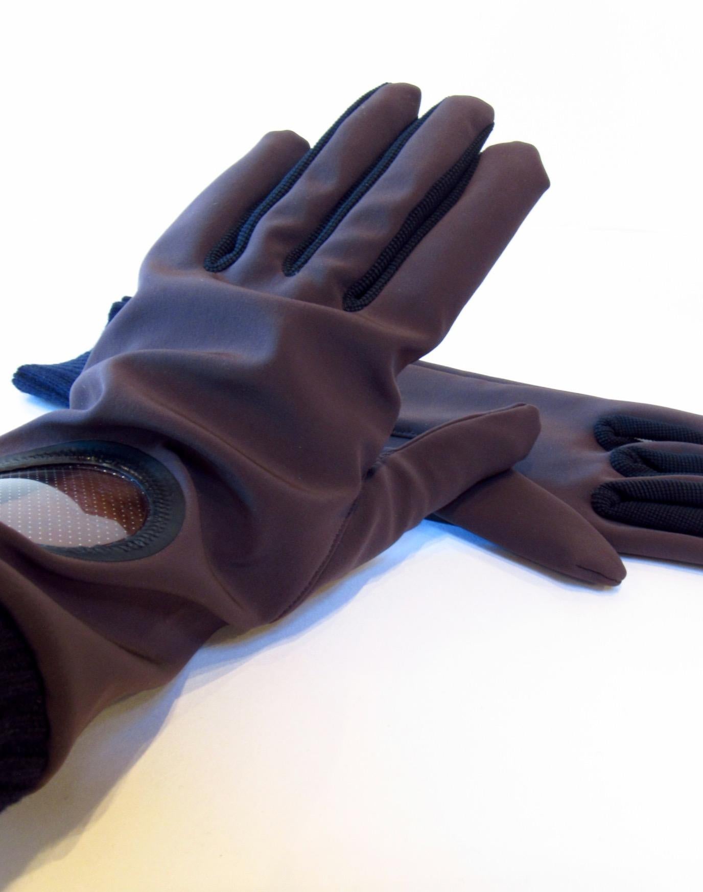 Vintage Undercover dunkelbraune Handschuhe aus Nylon und Polyurethan mit Bullaugenfenster am linken Handgelenk. Das Braun wird durch schwarze Wollbündchen und Details zwischen den Fingern ausgeglichen.
