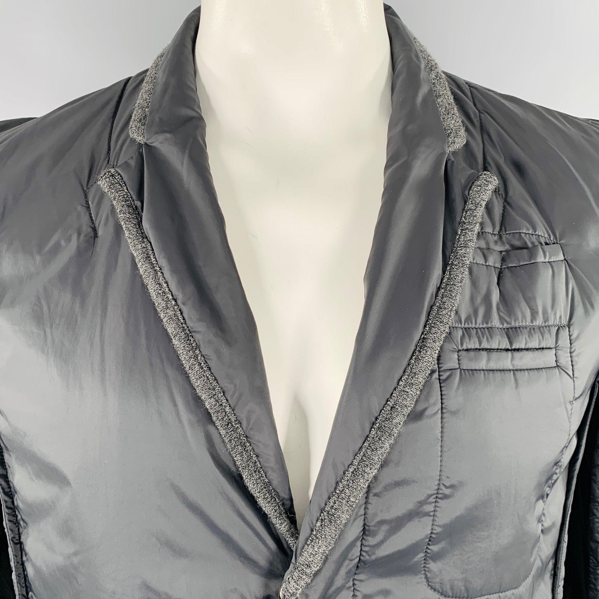 Chaqueta UNDERCOVER by JUN TAKAHASHI
en tejido de nailon negro, con solapa de muesca, ribete gris en contraste y cierre oculto con botones. Made in Japan. Muy buen estado de conservación. Marca menor. 

Marcado:   JP 5 

Medidas: 
 
Hombro 16,5