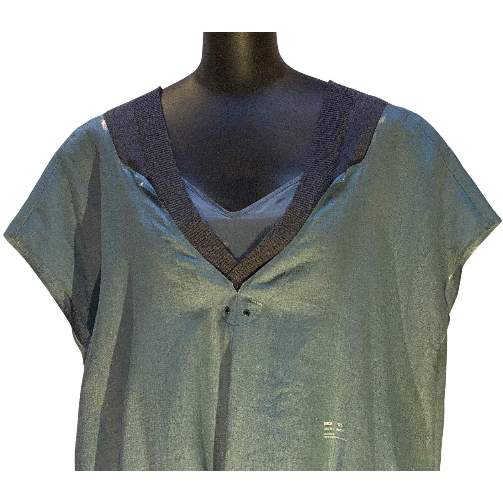 This beautiful soft, flowy blue-grey light linen tunic features a matching slip beneath. The v-neckline is highlighted, in front and back, by a contrasting grey cotton knit trim and grommet detailing. There are two side slit pockets. A discreet