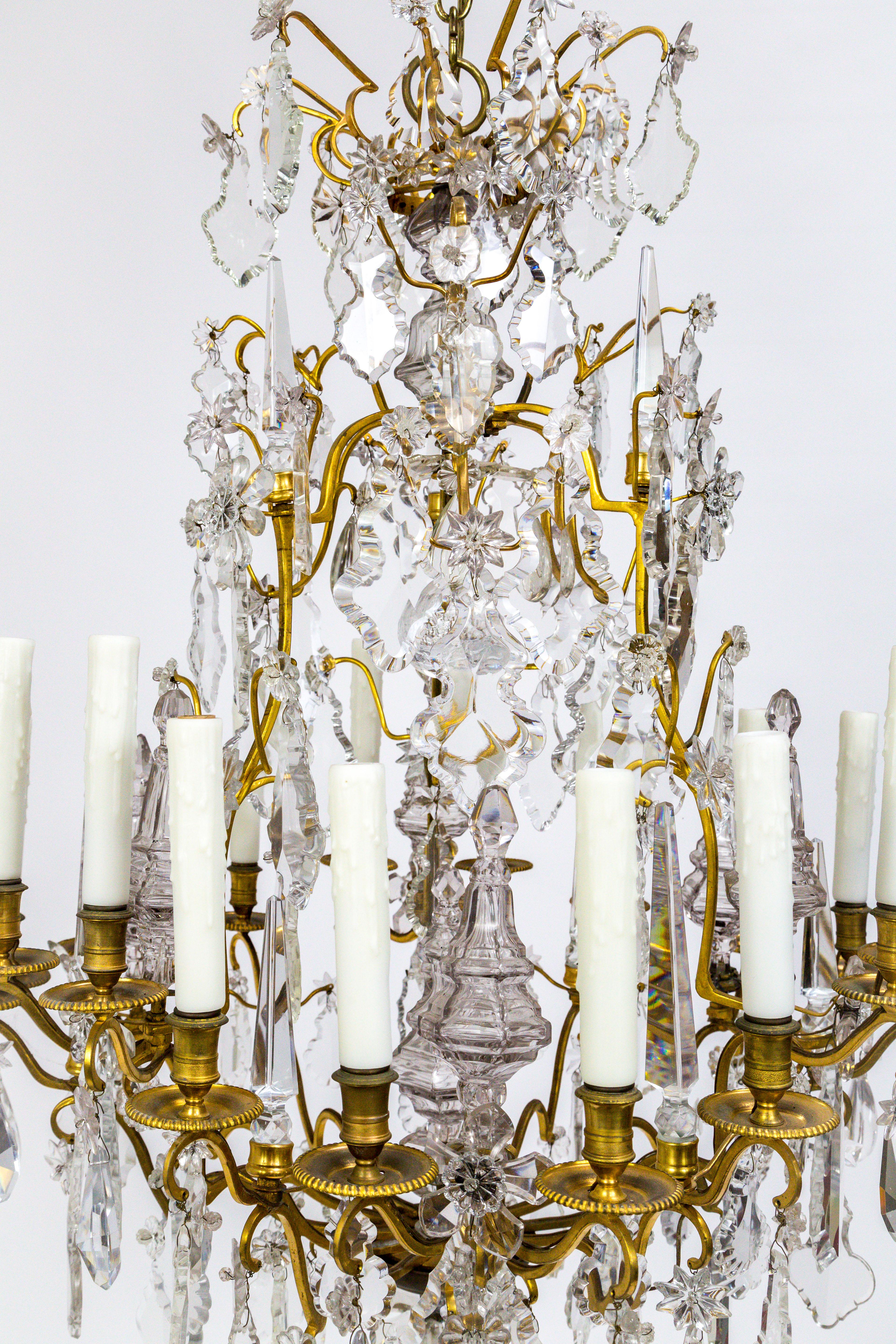 A magnificent, gilt bronze chandelier with eighteen undulating arms; decked with spire, star, spear, flower, almond, and pendeloque crystals. Decorated bobeches seen from the underside, American, 1900. Newly rewired and restored; with polyresin