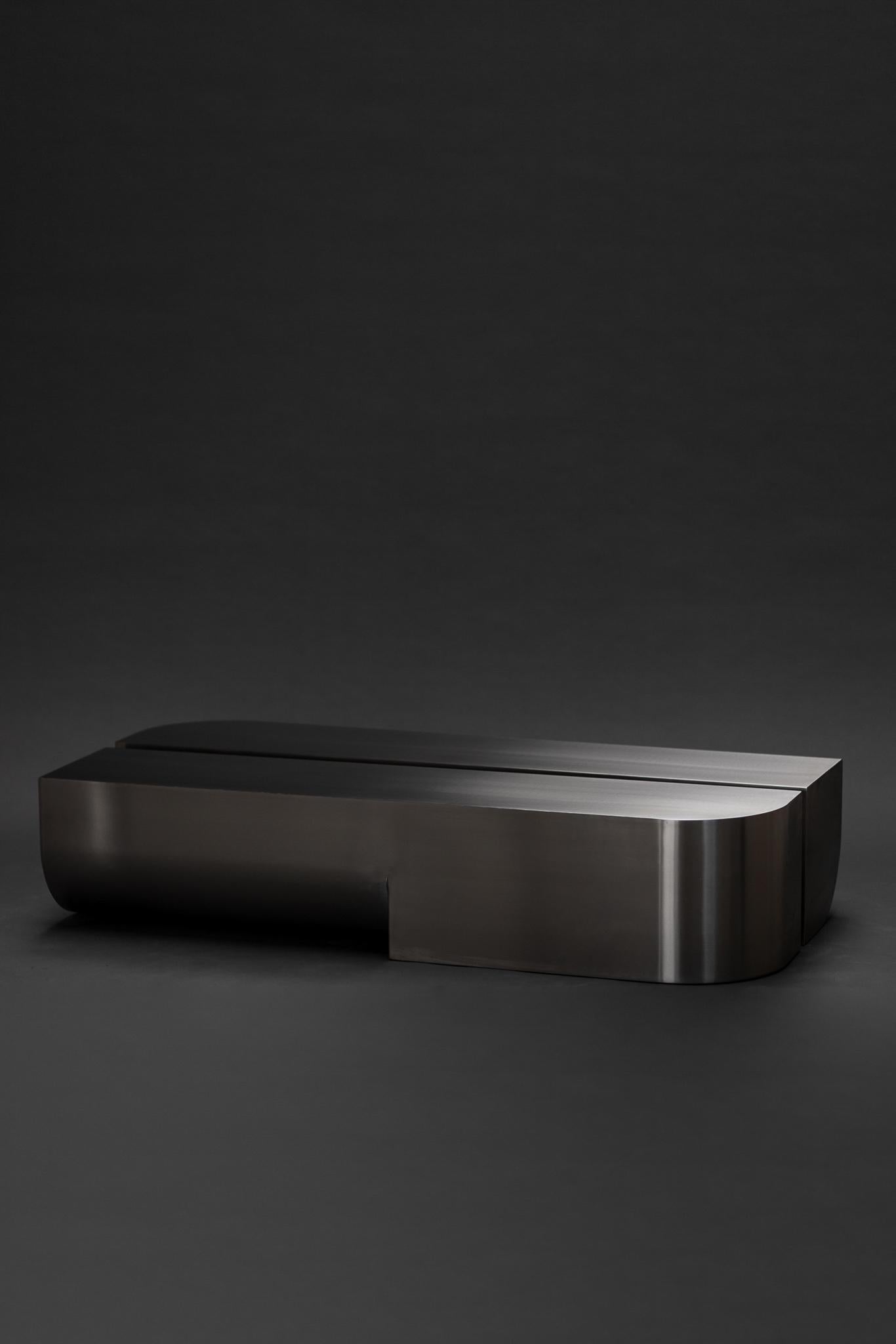 Undum Coffee Table by ​HADGE
Dimensions: D 32 x W 150 x H 32 cm.
Materials: Brushed stainless steel.
Also available in different materials.

A cohesion of simplified curved shapes in different directions reflects the passage of passing by and