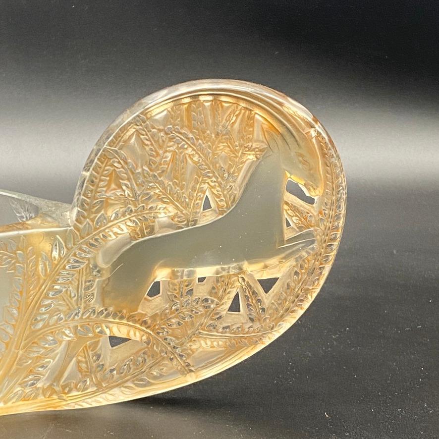 The Saint Hubert table center was designed in white glass by R.lalique in 1927.

It is one of the three table centers R.Lalique has designed and probably the most delicate .

The glass sides are delicately frosted as the handles are polished and