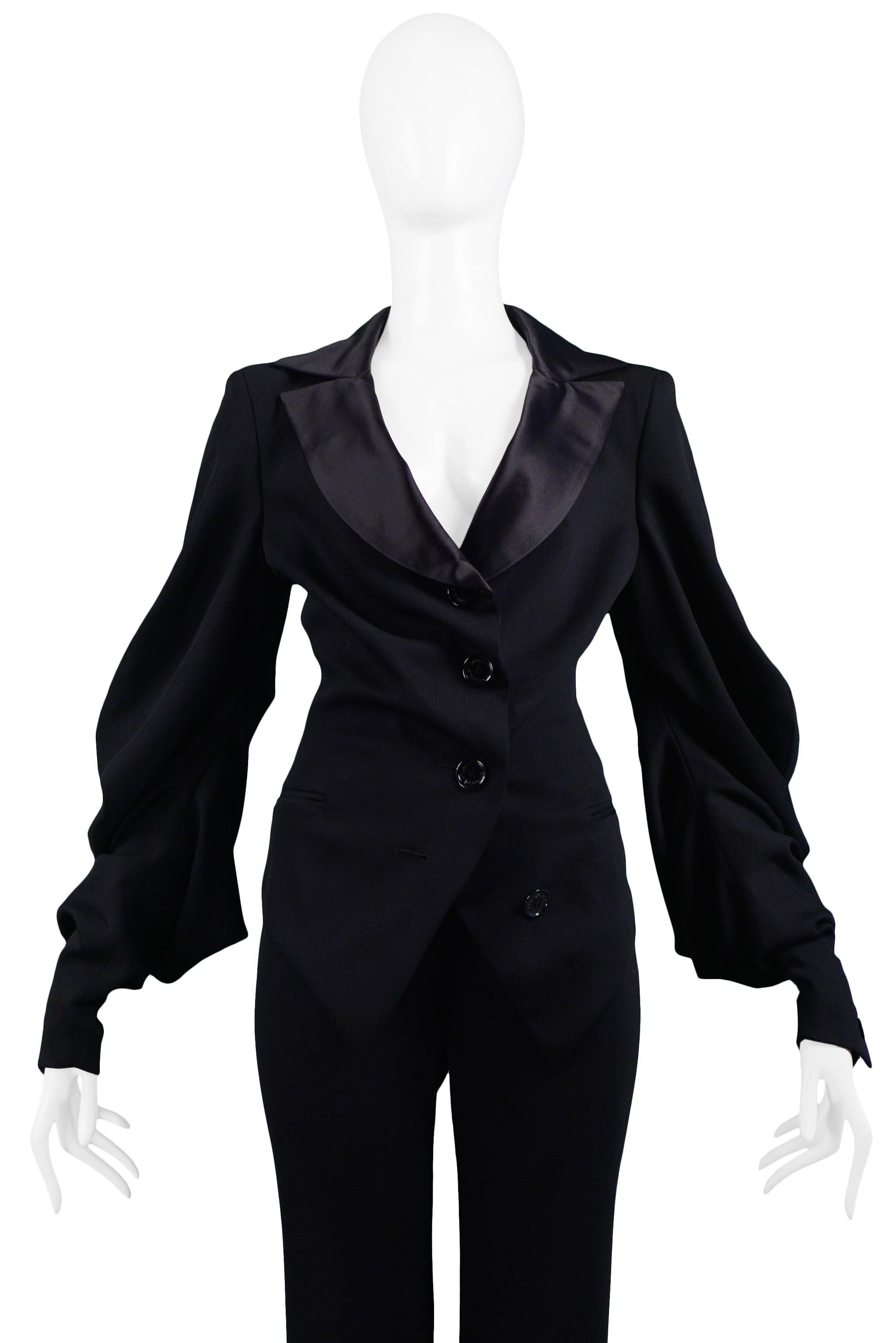 Resurrection Vintage is excited to offer a vintage Emanuel Ungaro black suit jacket and trouser ensemble. The jacket features a plunging neckline, black satin collar, gathered button front closure, and dramatic bishop sleeves. The pants are high