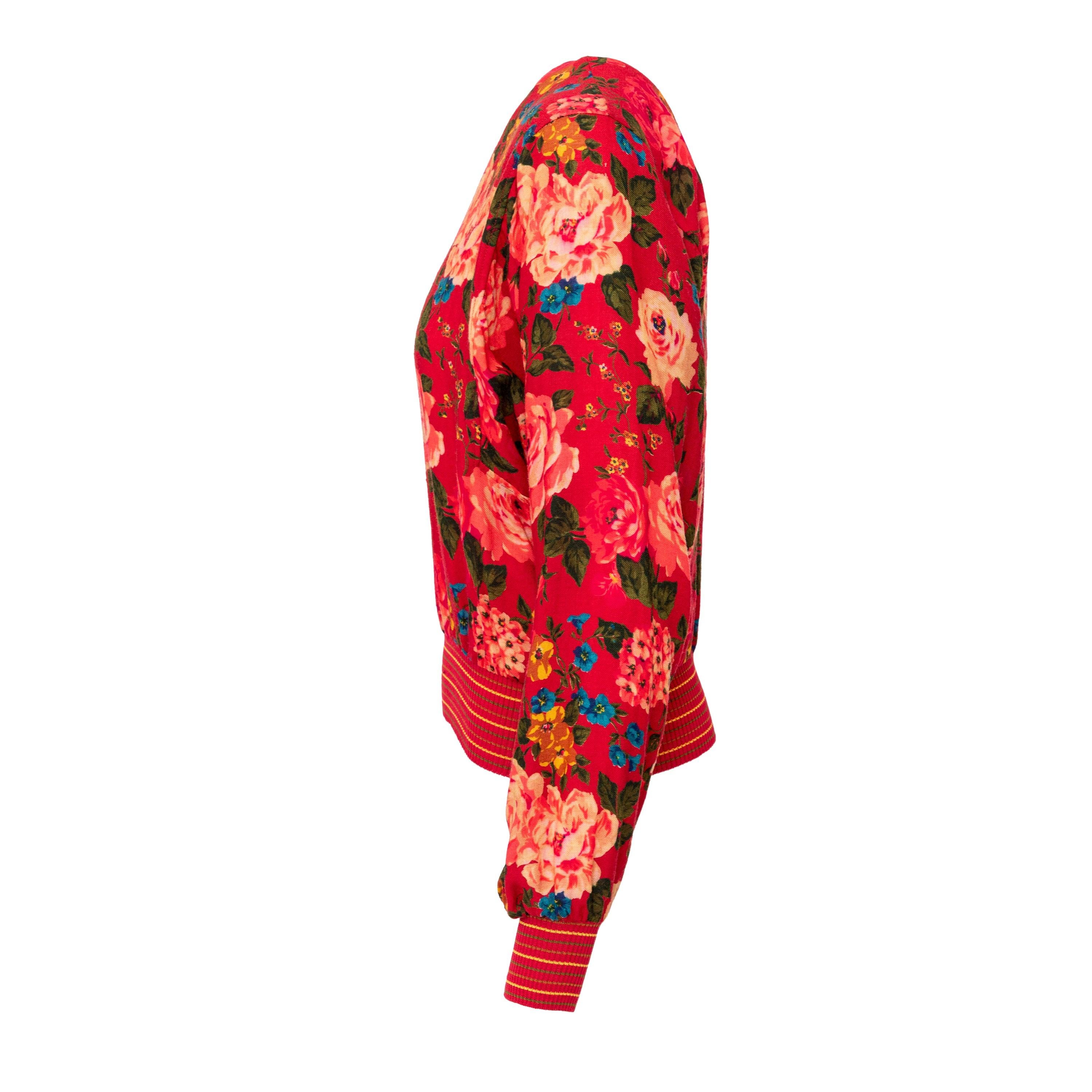 Upgrade your wardrobe with this vintage Ungaro Floral Printed Wool Top. Made of a luxurious wool blend, this sweater top features a ribbed hem, a round neck with a half button closure, and a stunning multicolour flower print on a bold red fabric. 
