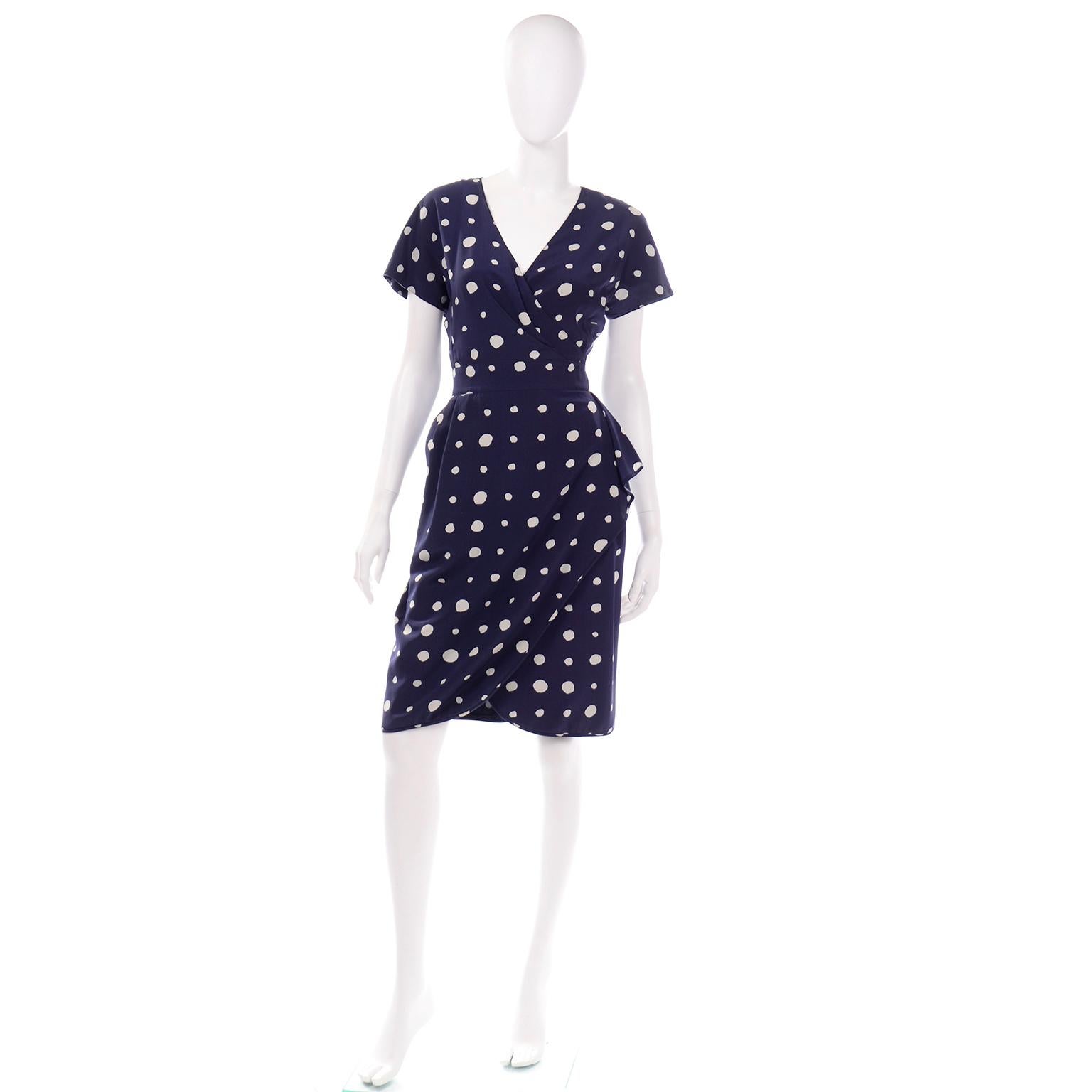 This is a vintage navy blue and white polka dot  silk day dress designed by Emanuel Ungaro in a faux wrap style. This late 20th century dress would be perfect to wear as a wedding guest to a summer wedding, out to lunch with a friend or even to