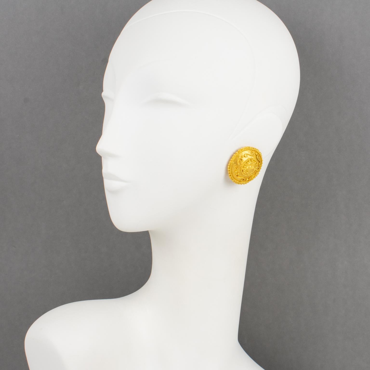 These stylish Emanuel Ungaro Paris couture clip-on earrings feature a gilt metal domed, rounded shape with a geometric carved pattern and satin-finish texture. The Ungaro—Paris—Made in France signature tag is on the underside of each earring.
The