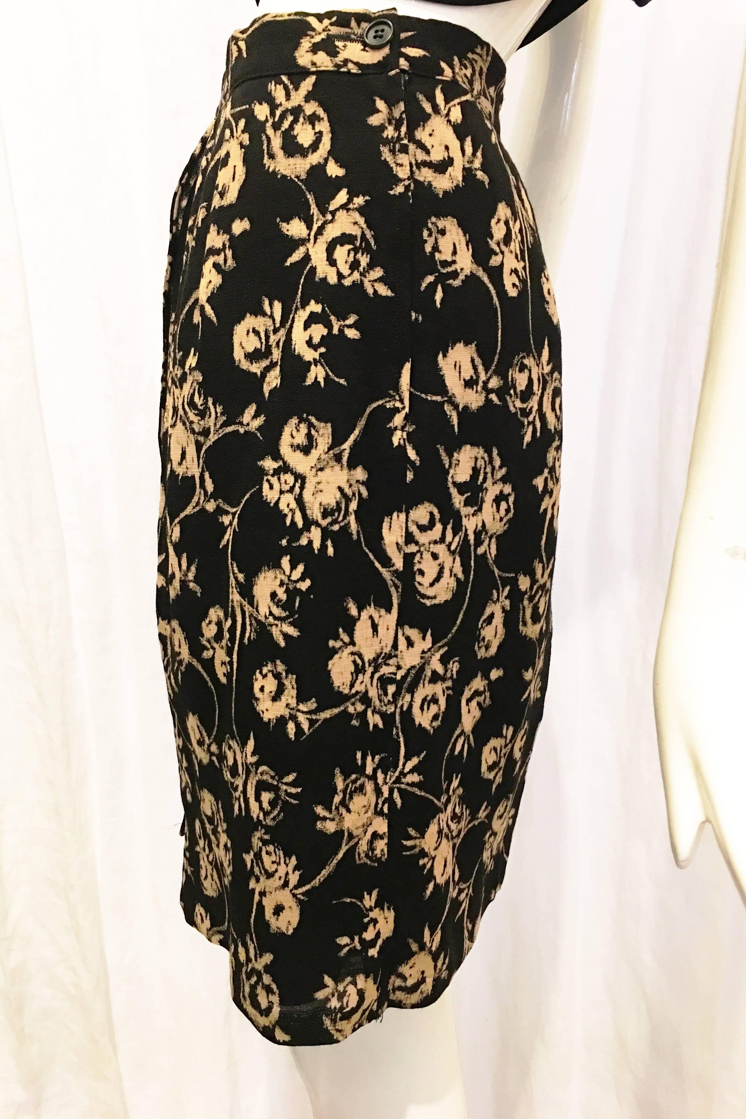 Black wraparound effect skirt with allover beige floral print. Fully lined. Lace on inner trim of hem. Zips and buttons at back waist of skirt. Simple, comfortable and versatile skirt for wear in a variety of settings. Pair with a cropped blazer,