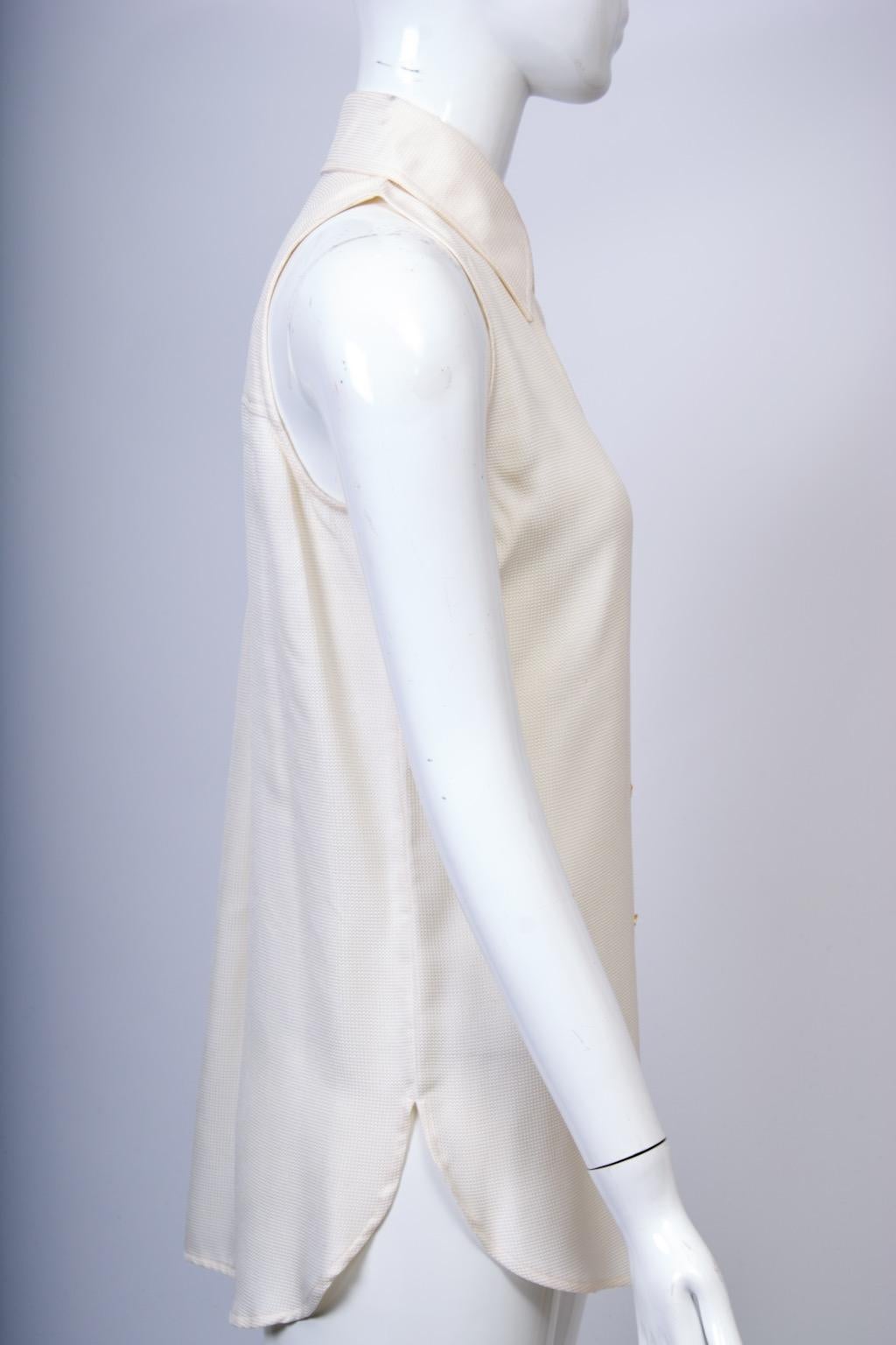 Chemisier sans manches en soie légère gaufrée d'Ungaro, c.fin des années 1980-début des années 1990. La chemise présente des boutons monogrammés dorés sur une patte de boutonnage qui va du col pointu à l'ourlet, qui est incurvé sur les côtés. Parmi