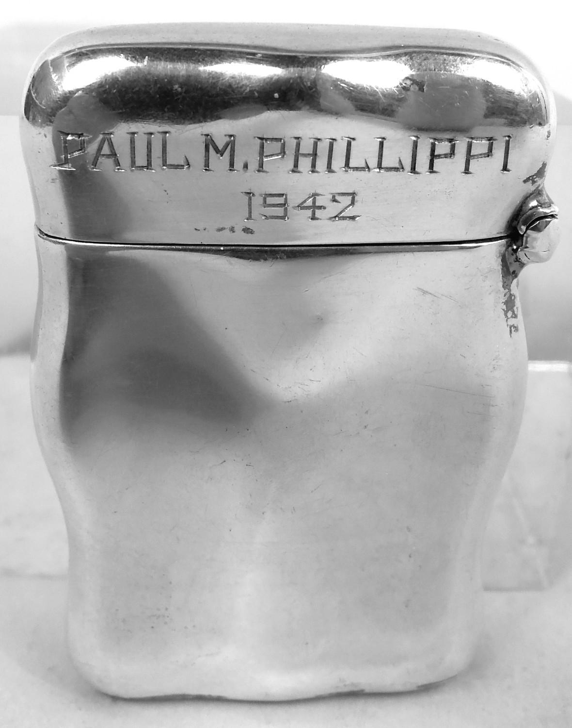 Art Nouveau sterling silver match safe. Made by Unger Bros in Newark, ca 1900. Shaped rectangle with hinged cover. On front an ethereal nymph lights up a cigarette against a smoke-filled scrolling background; back plain with engraved name and year