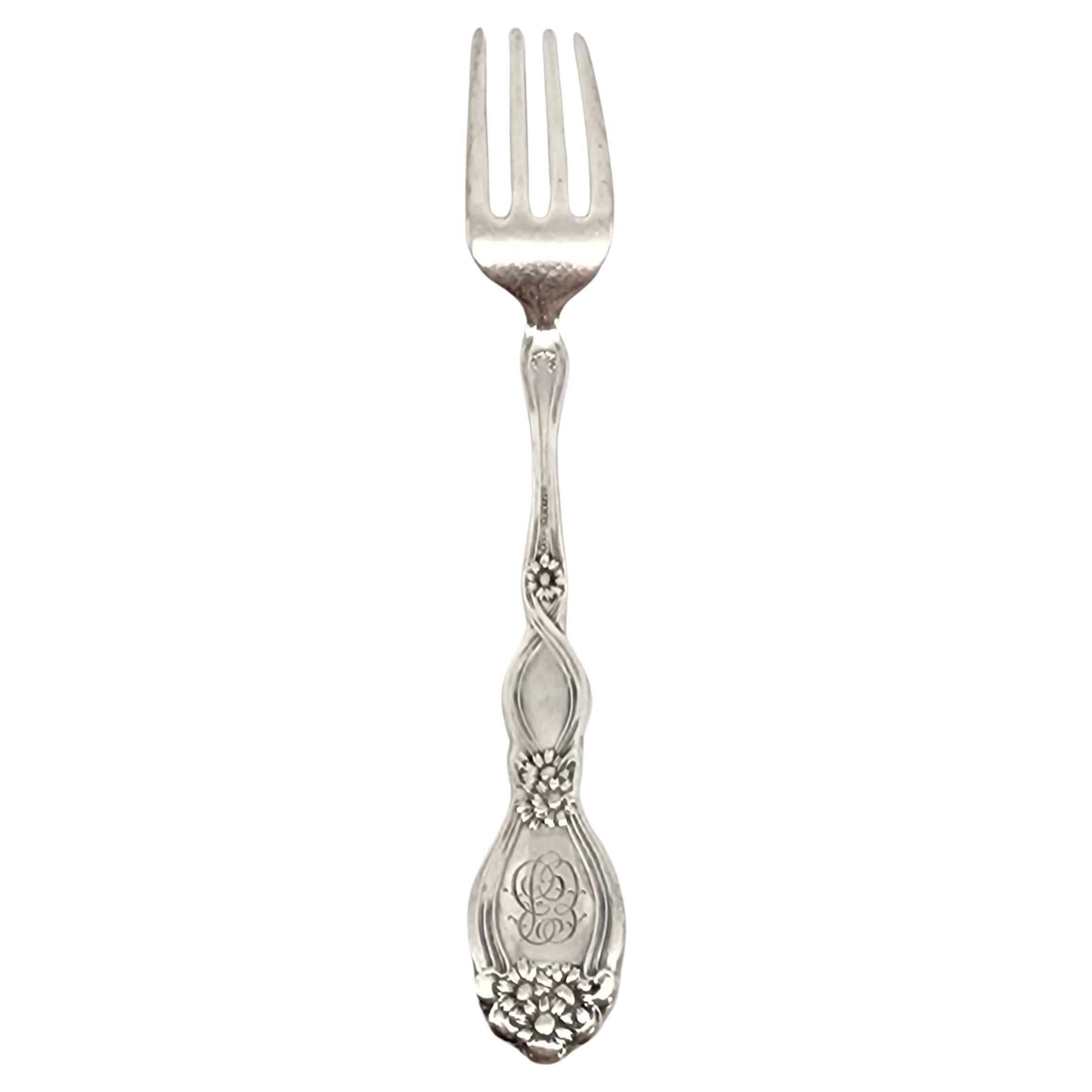 Sterling silver fork by Unger Brothers in the He Loves Me pattern, with monogram, circa 1904.

Monogram appears to be EB (on the back of the handle)

This fork features a girl on profile in flowers, with flower detail on the back of the