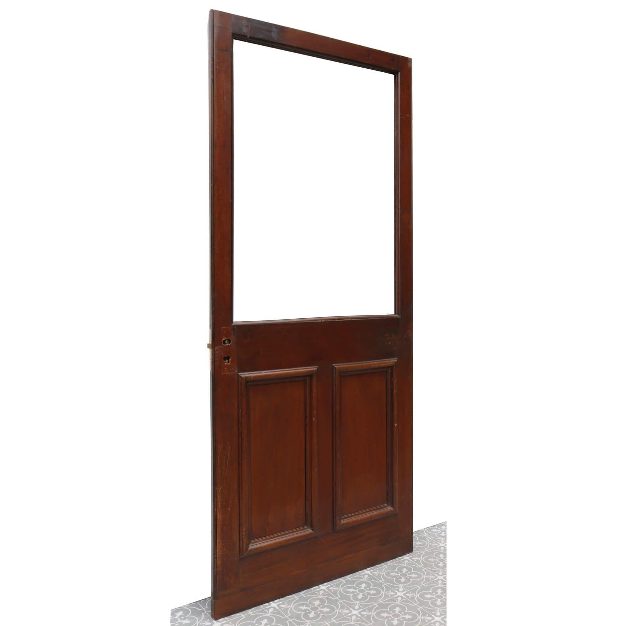 This unglazed reclaimed mahogany door dates from the Victorian era. It is over 130 years old and is in good structural condition featuring gunstock construction and a rich mahogany wood finish. The bottom half of the door is detailed with a pair of