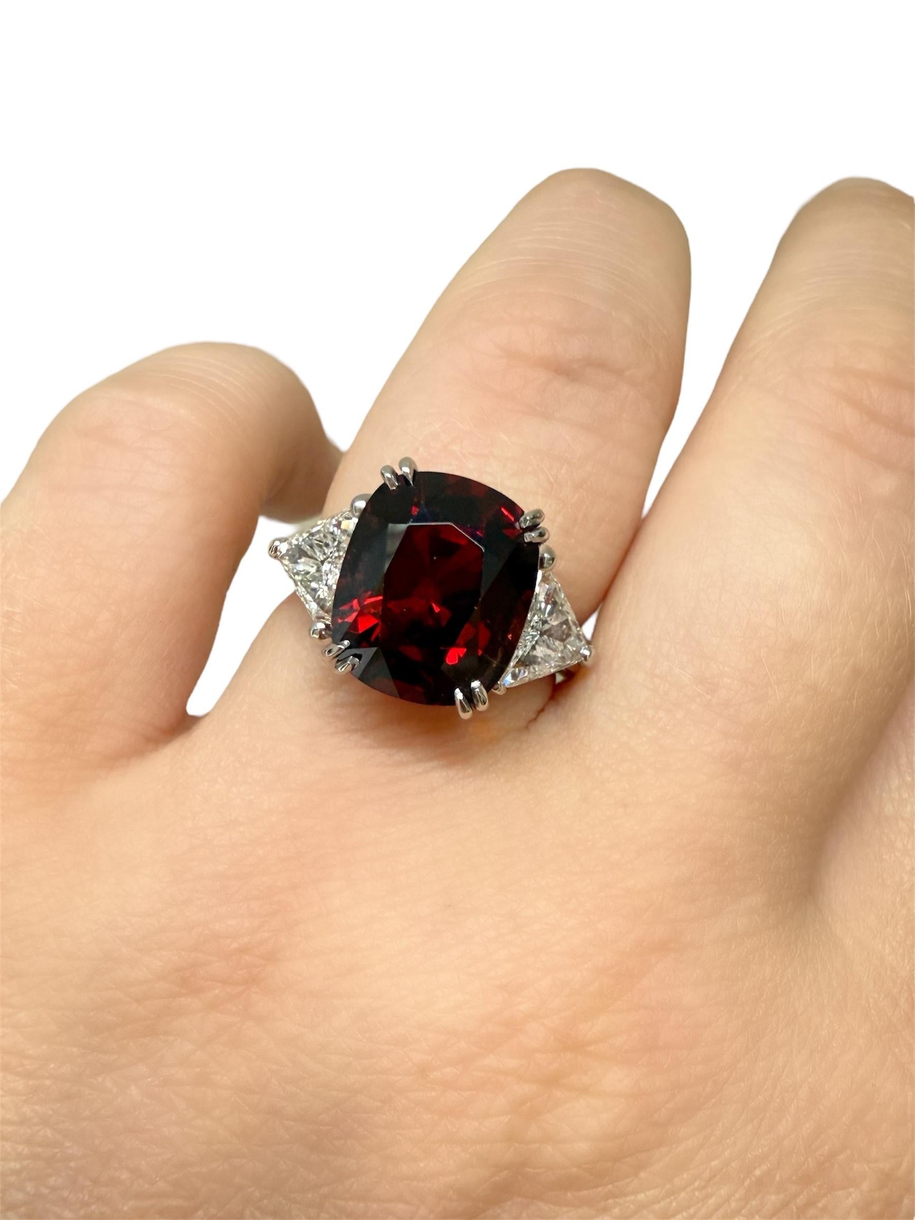 This stunning ring contains an antique cushion spinel weighing 6.93 carats and measuring 11.95 x 10.00 x 7.66 mm, flanked by two trillion cut diamonds weighing 1.20 carats total. Mounted in a beautifully made platinum mounting with double claw