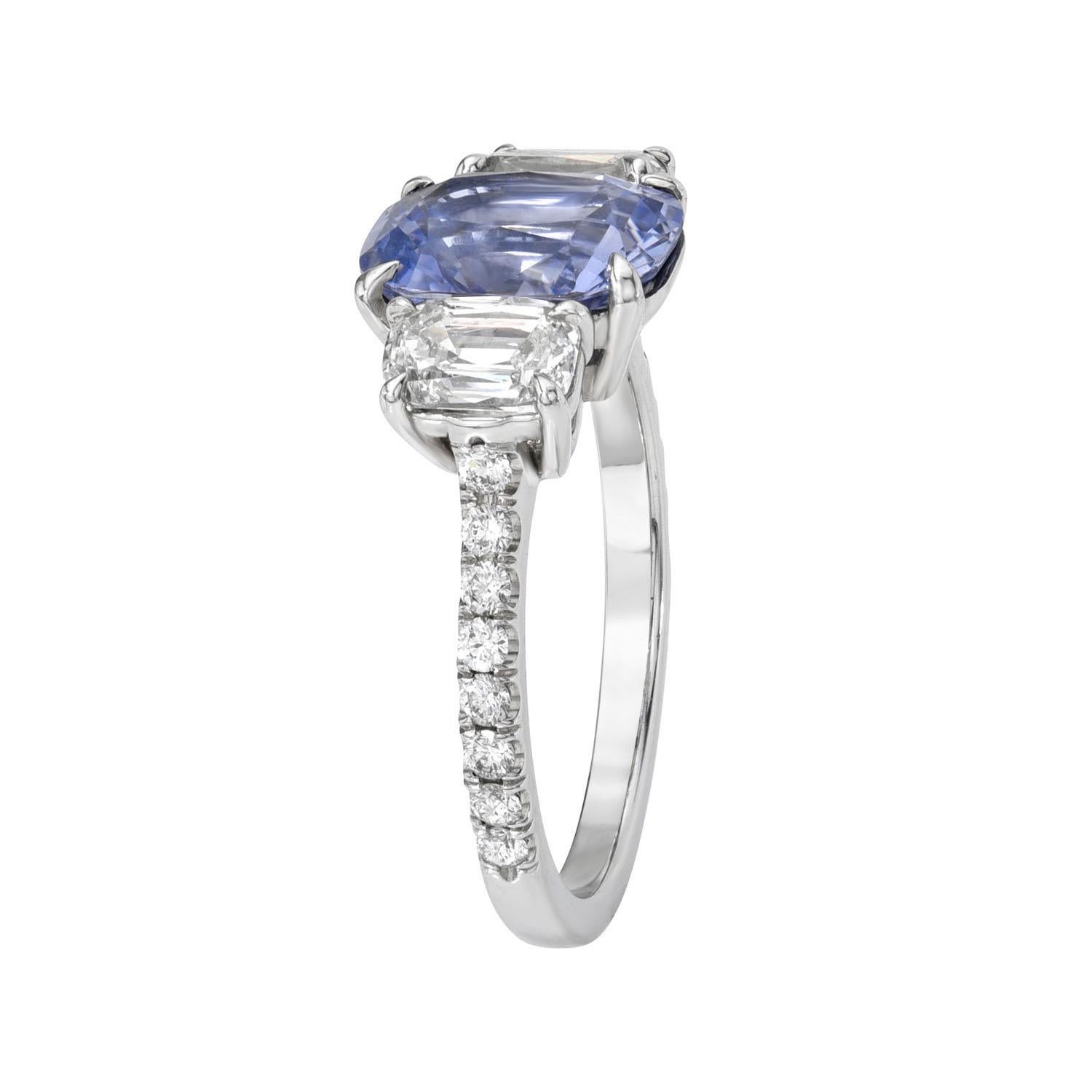 Vibrant and unique 2.79 carat unheated Blue Sapphire cushion, three stone platinum ring, flanked by a pair of 1.07 carat, I/SI1 cushion diamonds and a total of 0.24 carats of round brilliant diamonds
Ring size 6. Resizing is complementary upon
