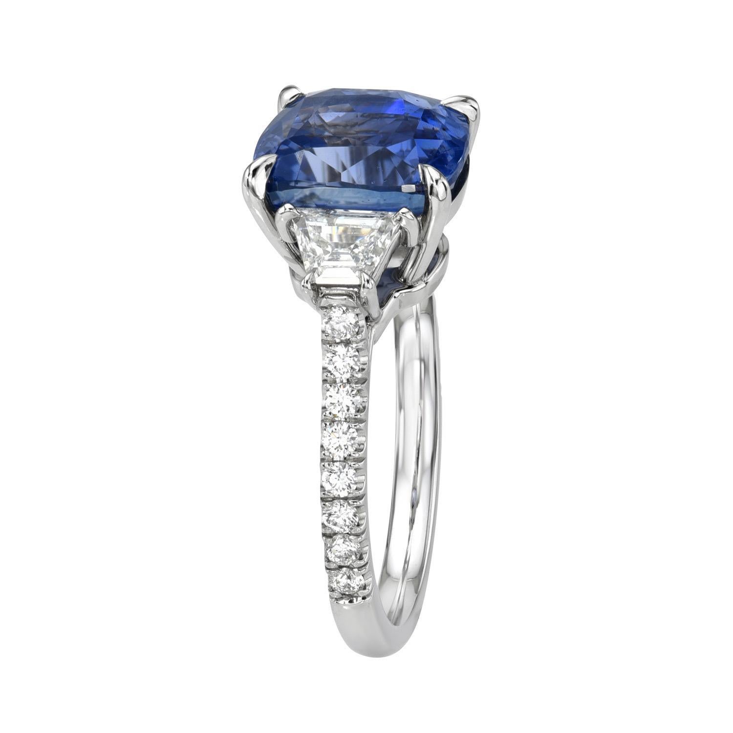 Splendid 5.59 carat Unheated Ceylon Blue Sapphire cushion, three stone platinum ring, flanked by a pair of 0.45 carat, F/SI1 Trapezoid diamonds and a total of 0.25 carats round brilliant diamonds.
Ring size 6. Resizing is complementary upon