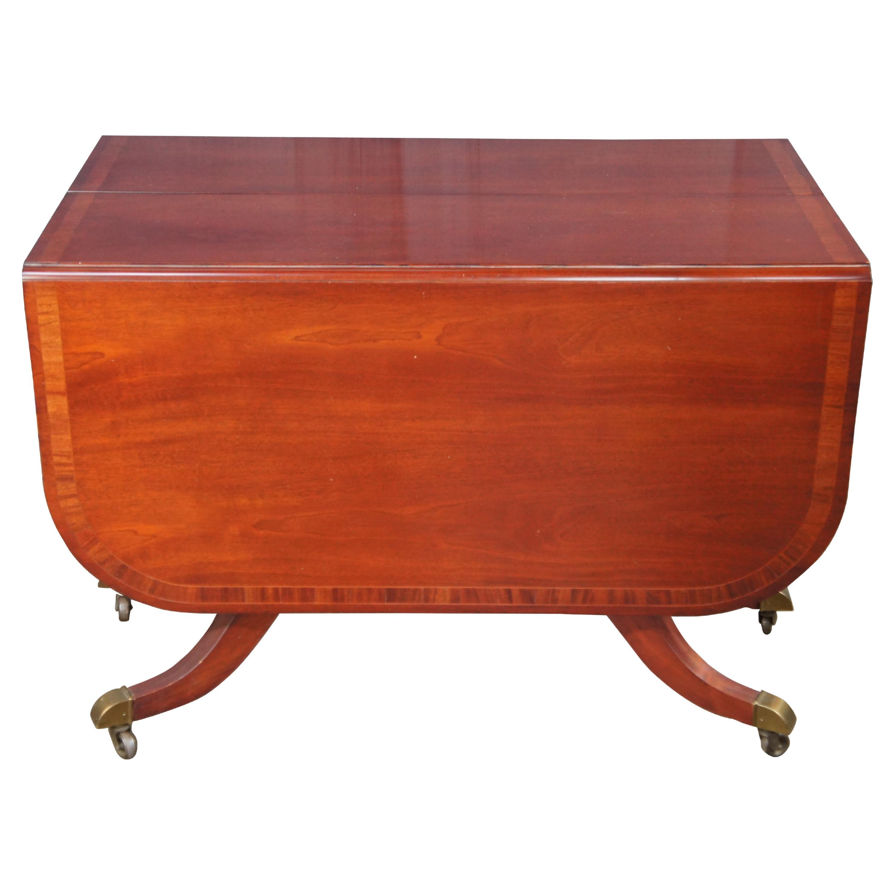 Mid-20th Century Union National Duncan Phyfe Style Drop Leaf Extendable Dining Table.  Made from American mahogany with a banded top.    Features a harp or lyre carved pedestal base leading to six downswept legs with brass capped feet and castors. 
