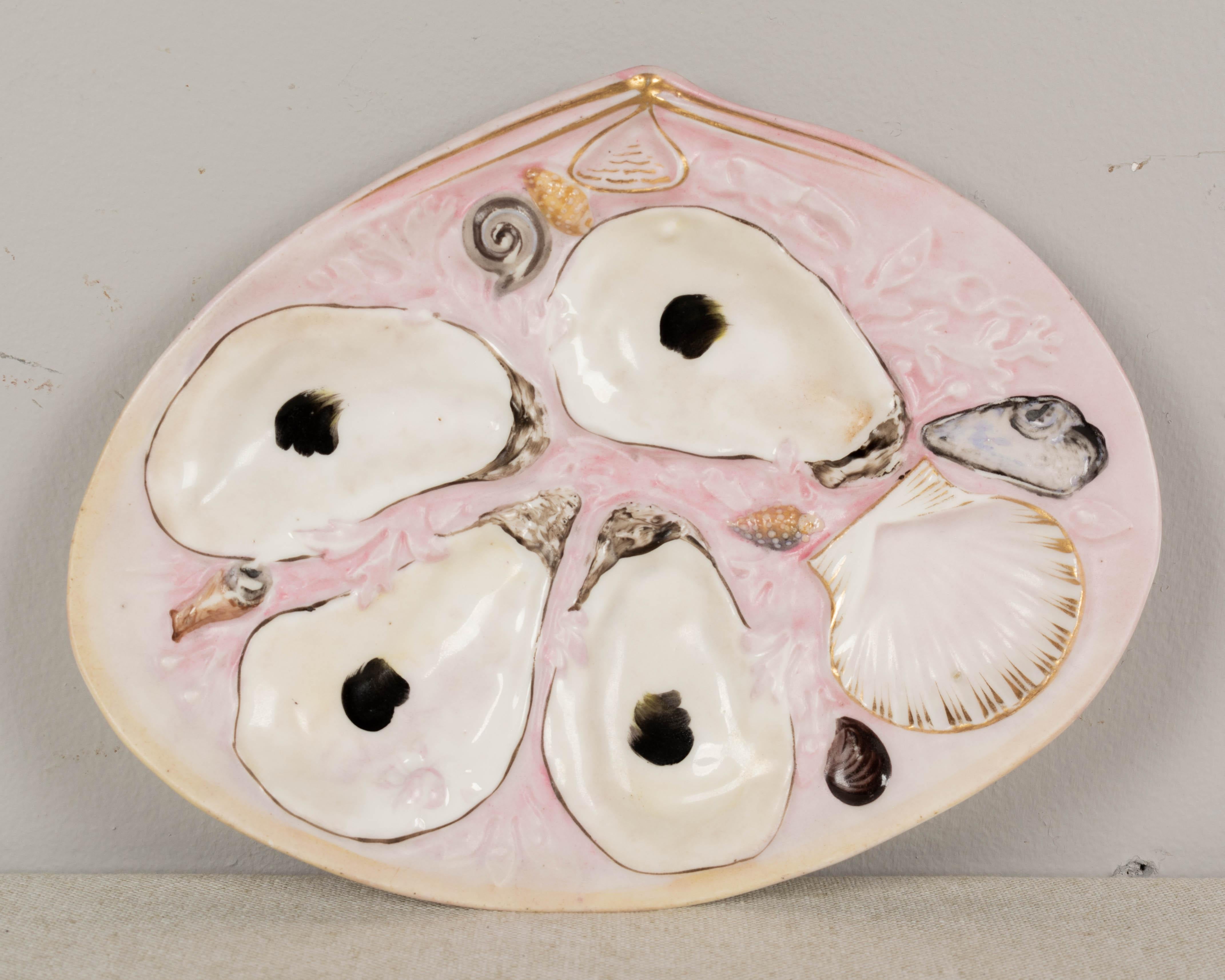 A set of four 19th century oyster plates made by the Union Porcelain Works of Greenpoint, New York. Hand-painted with pale pink ground and gilt accents. Nicely shaped and molded with four shallow wells for oysters and a scallop shell for sauce.