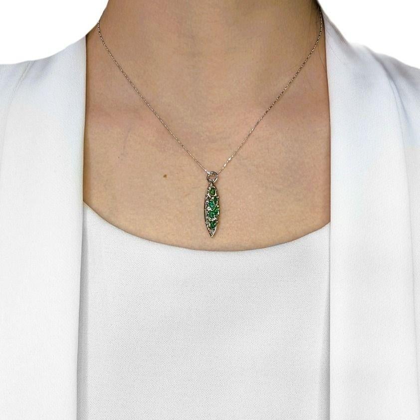 Impregnado de calidez y elegancia, este impresionante colgante de oro blanco de 9 quilates presenta seis cautivadoras esmeraldas de forma ovalada, con un total de 0,85 quilates, cada una de ellas con un intenso tono verde que simboliza la renovación