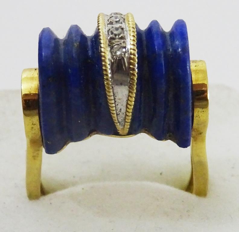 A very Unique Tank Ring originating in the 1940's.
The top is a carved Lapis in a very unique shape, along one of the ridges formed by the carving there is a decorative strap of white and yellow gold that has 5 2 point Diamonds set in it,.
The shank