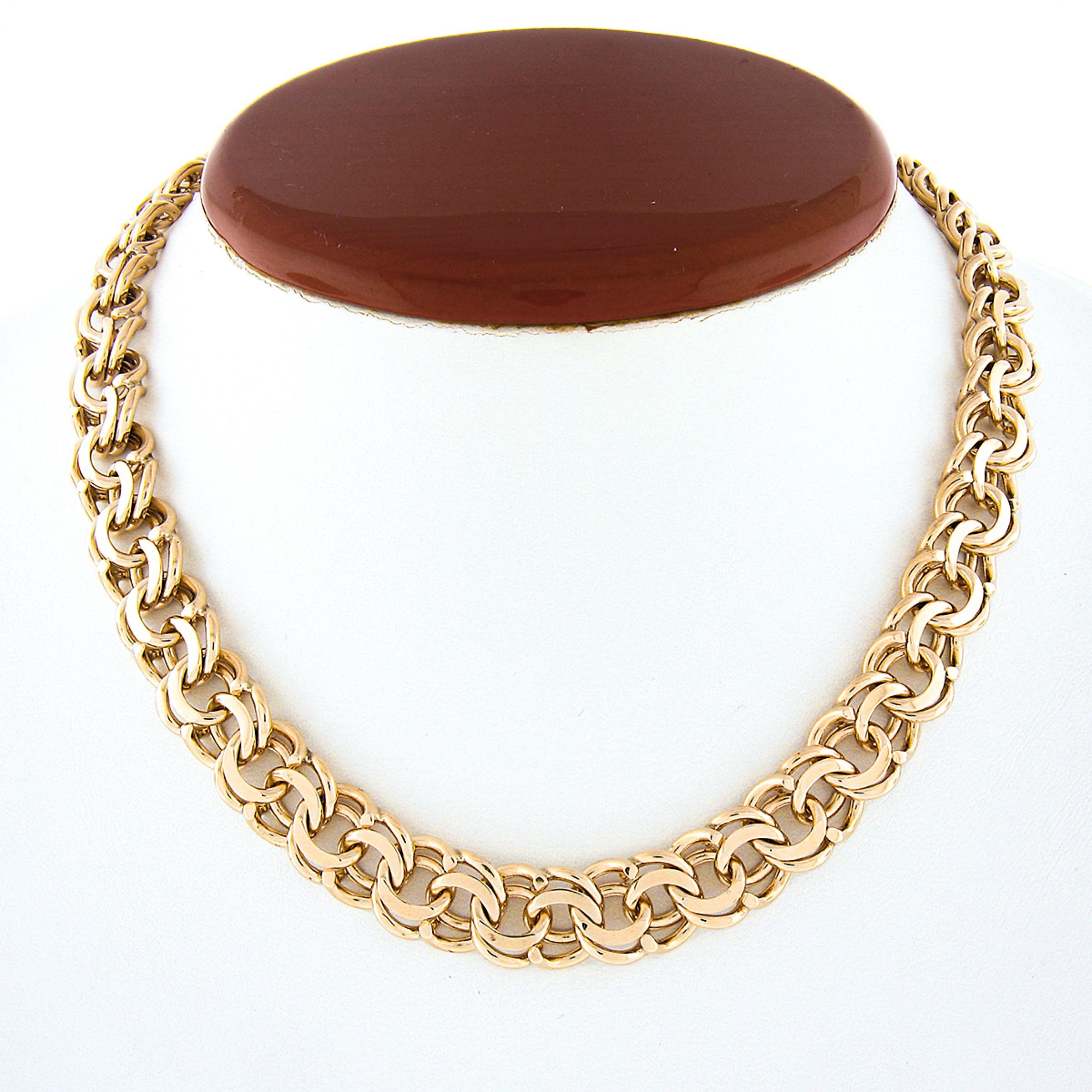 Ce magnifique collier ras du cou en or jaune 14 carats est composé d'une double boucle et d'un anneau ouvert avec une belle finition polie. Cette chaîne substantielle mesure 15,25 pouces en longueur portable et 11,2 mm de large, se posant à plat et