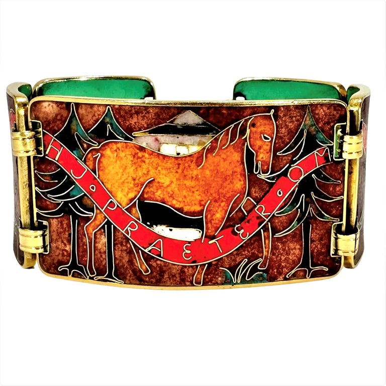 This wonderful 18K yellow gold, unique bisque finish enamel bracelet depicts a scene of various wild and domestic creatures in a forest setting. A red banner runs throughout all five bracelet links, bearing the Latin wording, 