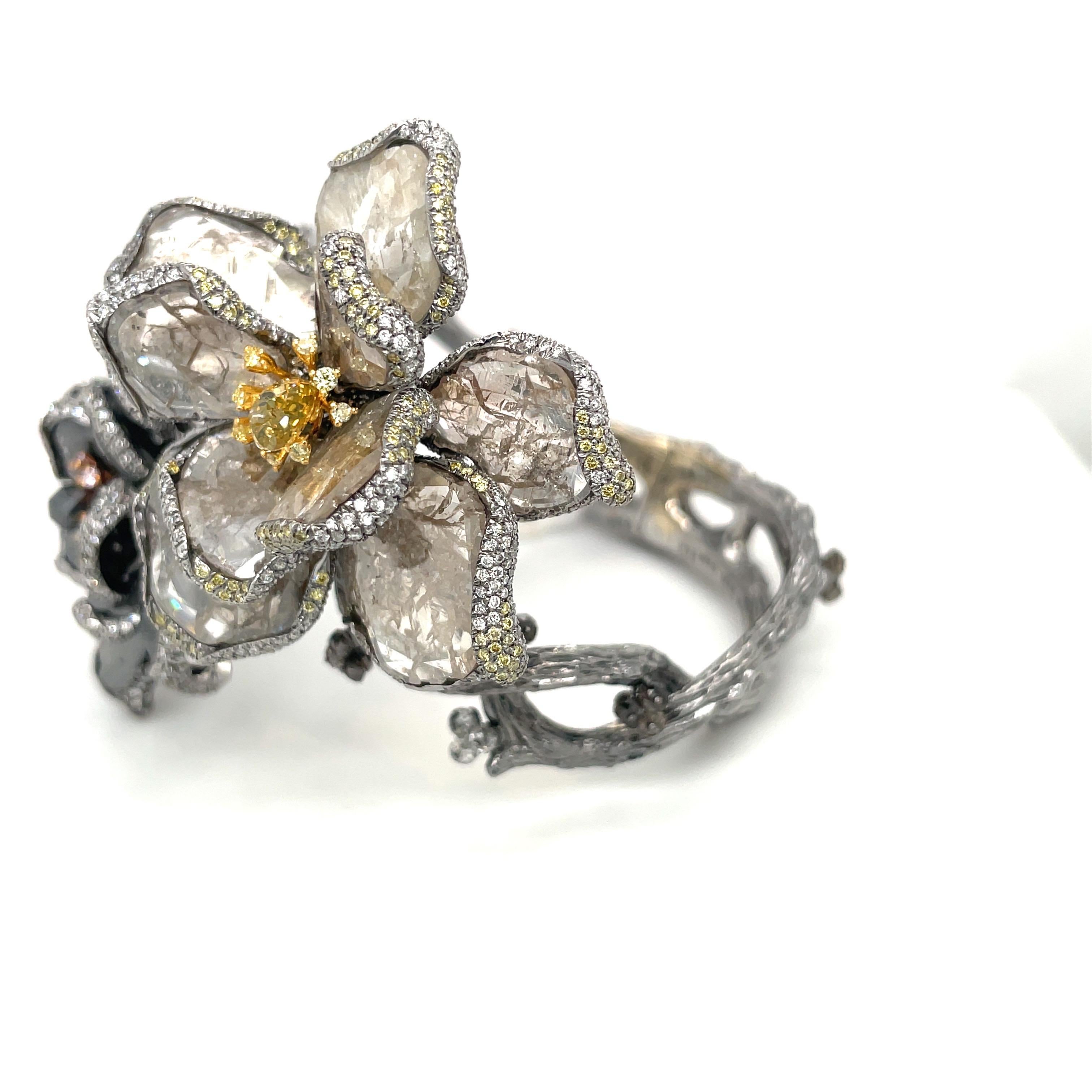 Ein wahres Kunstwerk!!
Dieses wunderschöne Armband ist aus 18 Karat geschwärztem Gold gefertigt. Die Zwillingsblüten sind mit braunen und schwarzen Diamantscheiben als Blütenblätter besetzt. Jedes Blütenblatt ist anmutig mit eingefassten Diamanten
