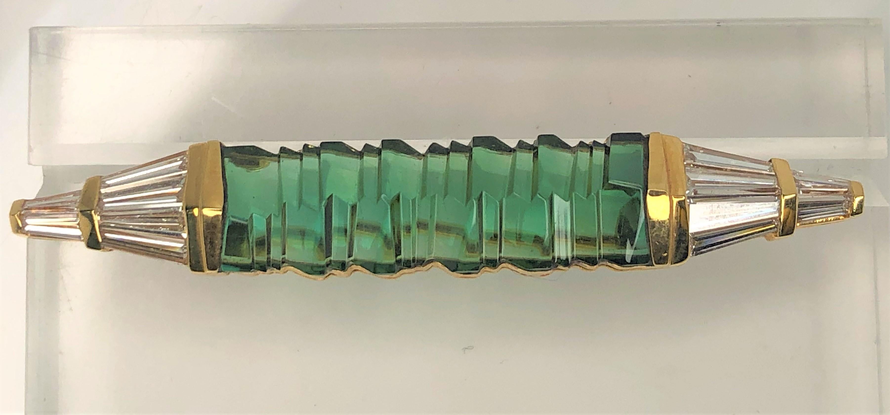This is without question a one-of-kind special cut green tourmaline and diamond brooch.
Green tourmaline, approximately 28mm x 9mm, special cut in an 'accordion' design.
Pointed ends of mounting set with tapered baguettes.  Approximately 1.20 total