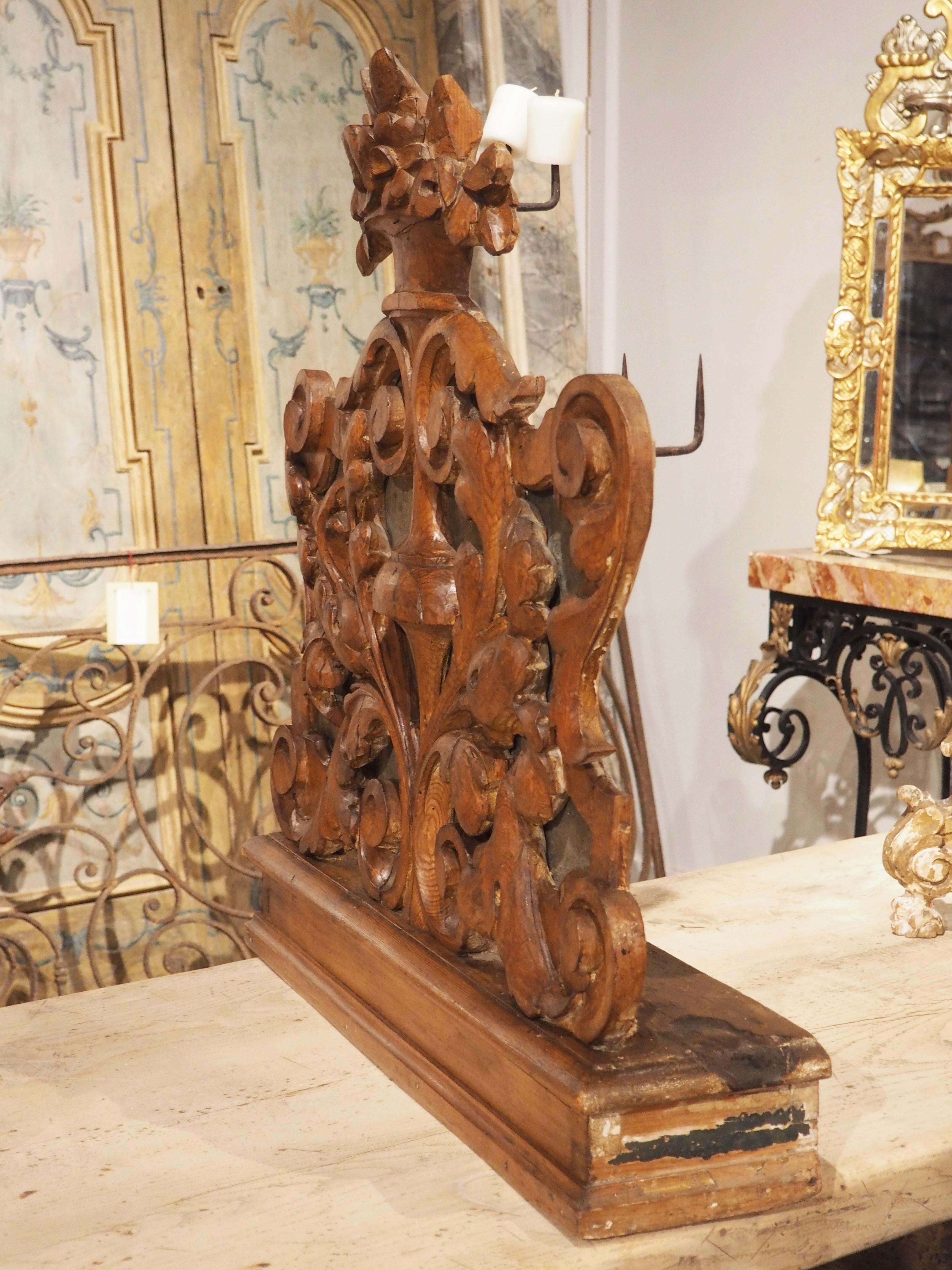 hand carved from pine in the 1700s, this unique Italian altar candlestick holder features a lovely foliate rinceaux dotted with volute scrolls. The intricate weaving of curled leaves is topped by a floral bouquet. There are seven iron prickets on