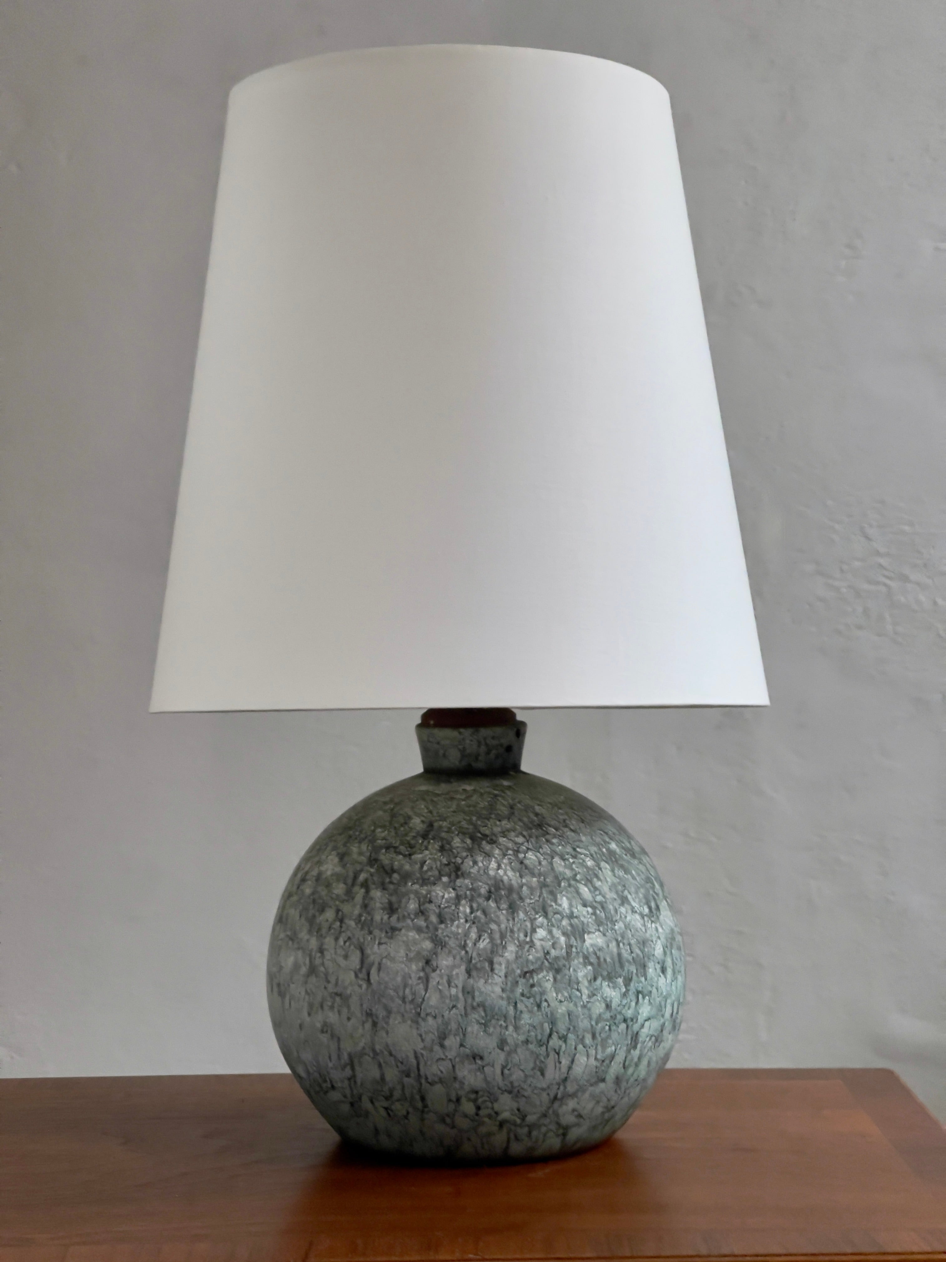Unique 1920s danish stoneware table lamp with light blue green matte glaze. 

(The lamp will be rewired with a fabric wire to 110 or 220 V plug)

In the dim corridors of time, where craftsmanship and artistic expression converged, we find ourselves