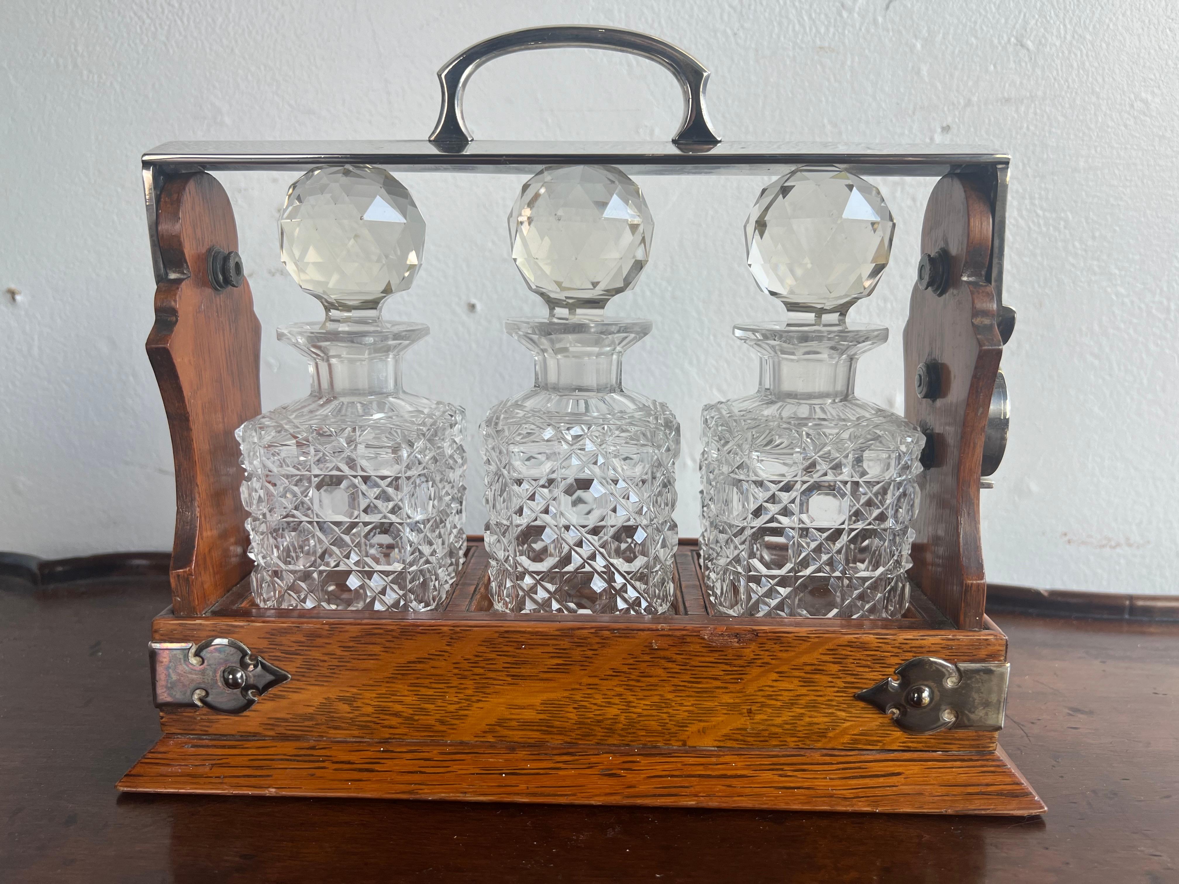 19th century English tantalus set in a rare petite size.  A tantalus is a decorative container, typically made of wood and metal. designed to securely hold and display glass & crystal decanters.  This set consists of:

1. Three cut-glass decanters