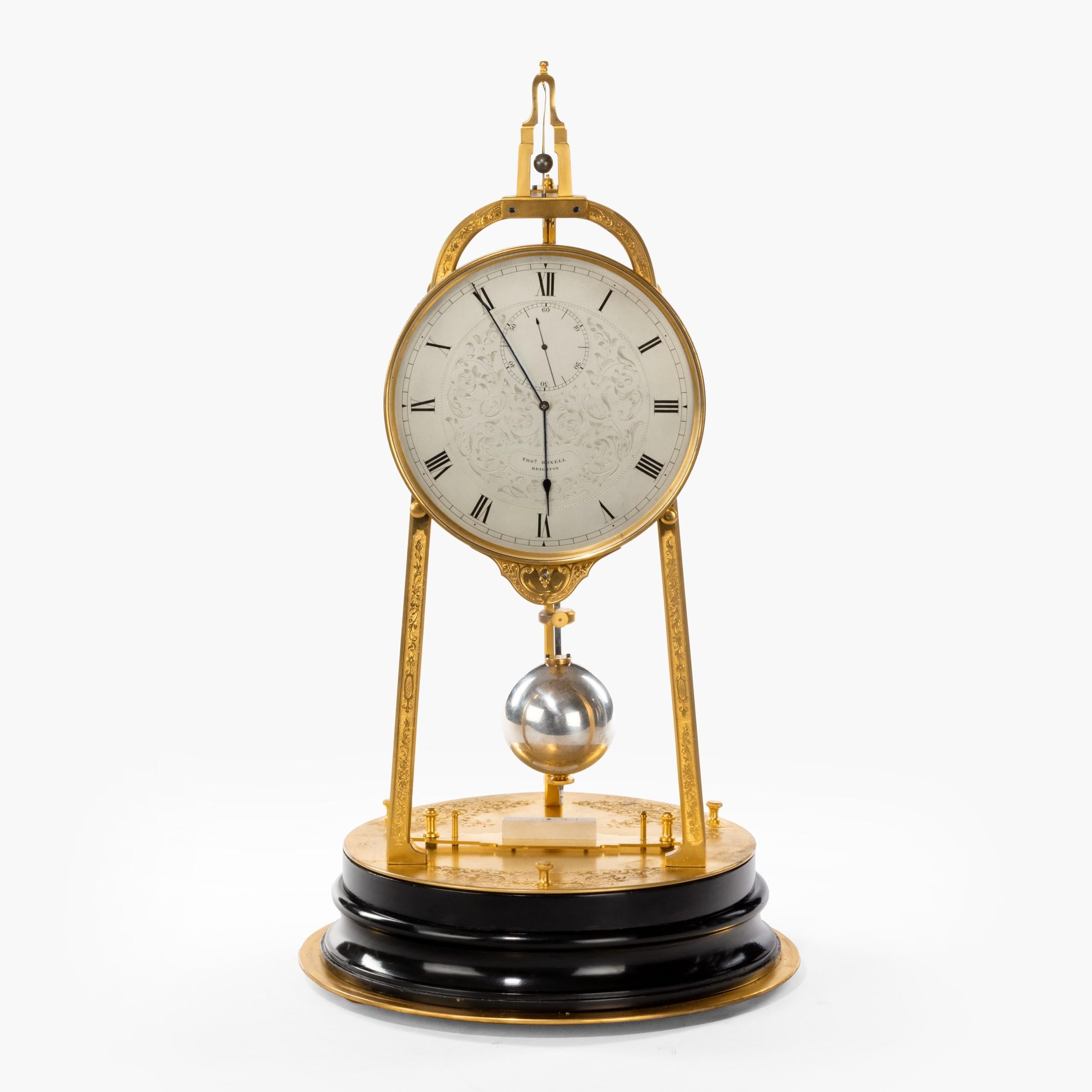 A rare tripod table clock by Thomas Cole
Retailed by Thomas Boxell of Brighton

The circular stepped dark ebonised base surmounted with a gilded panel having engraved foliate panels and three levelling screws, supporting three equidistantly