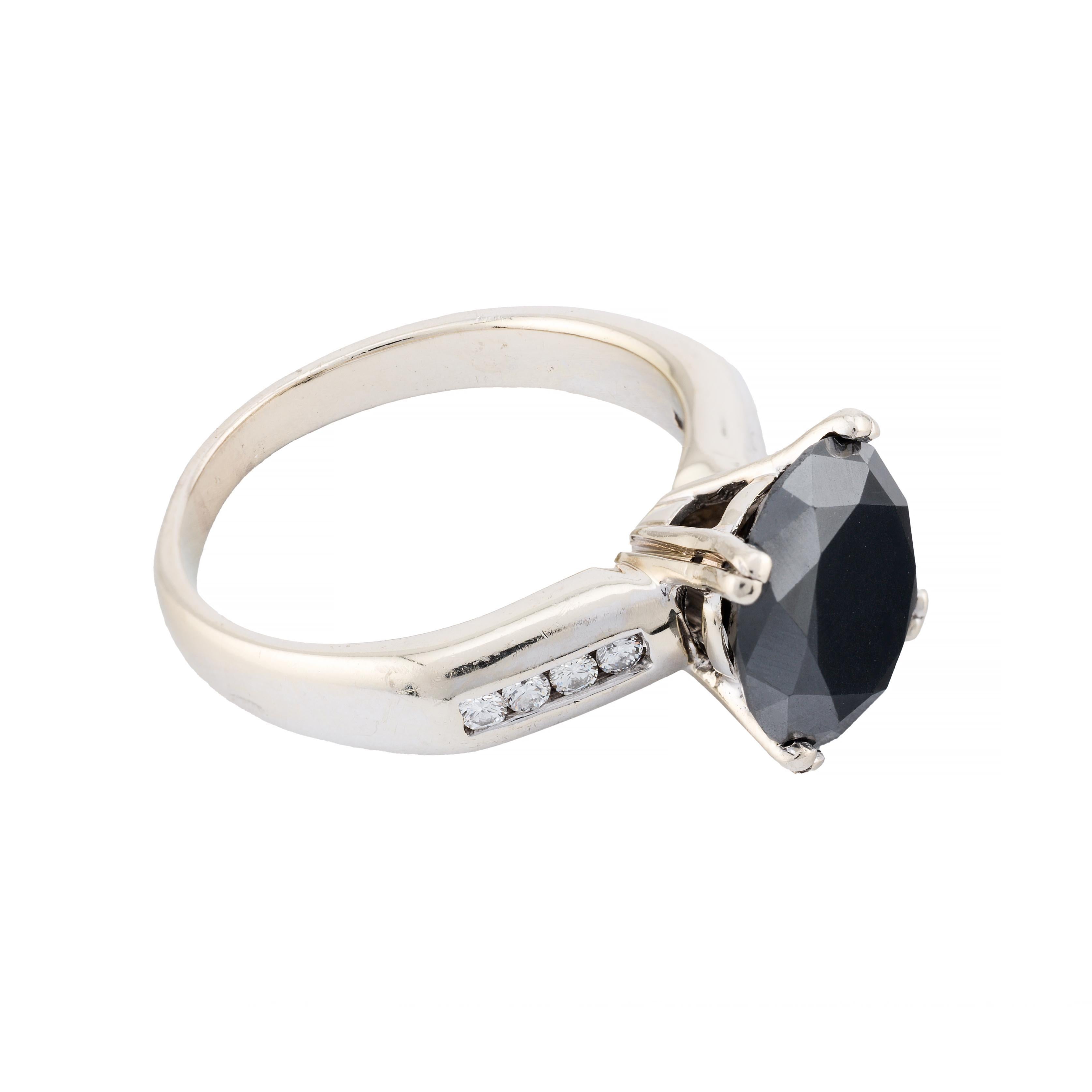 Aston Estate Jewelry stellt vor:

Ein fesselnder Verlobungsring mit einem schwarzen Naturdiamanten im Brillantschliff von 4,00 Karat.

Der schwarze Diamant ist elegant in ein Band aus 14 Karat Weißgold gefasst, das mit 0,16 Karat weißen Diamanten im