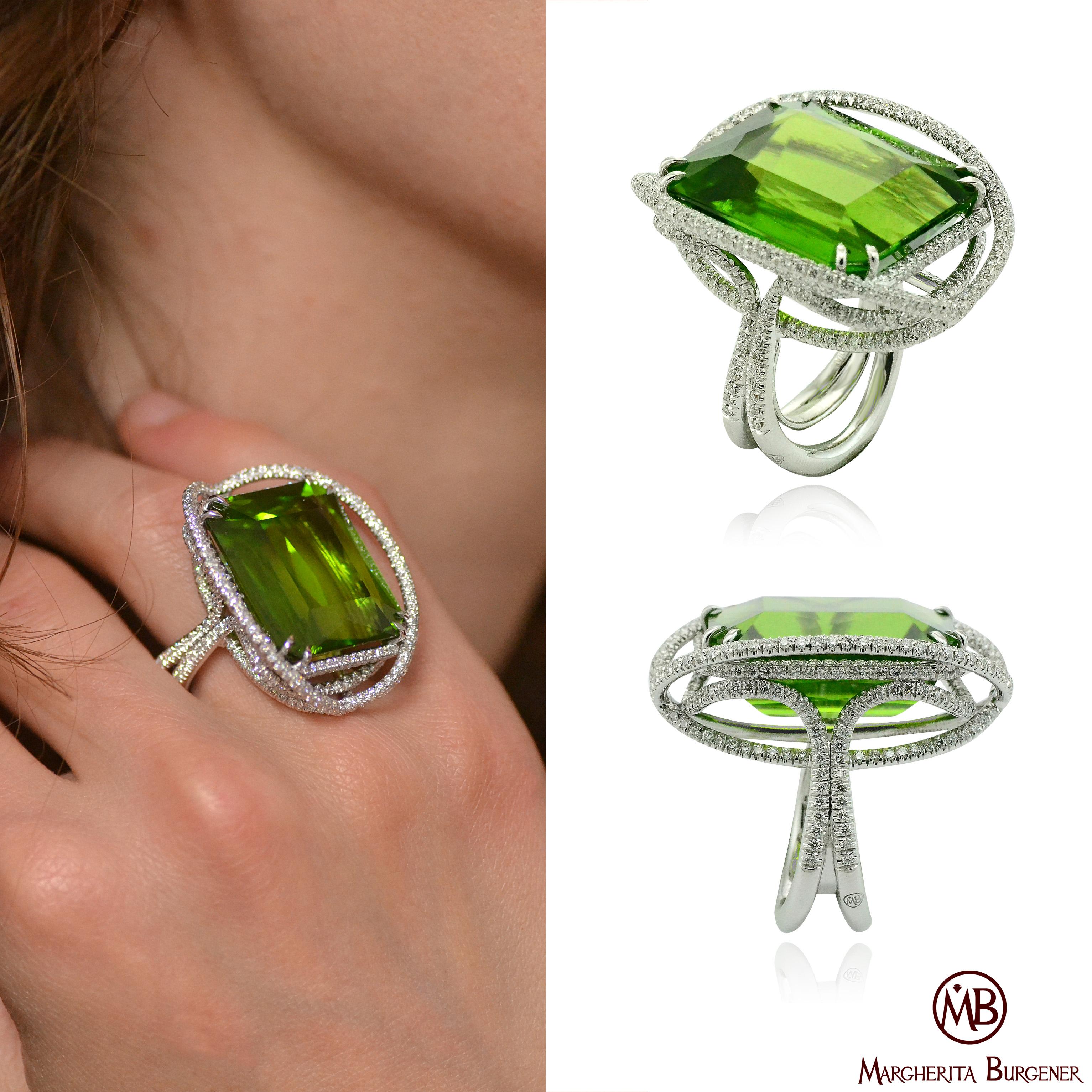 An impressive Peridot of Burma origin, weighing 53.50 carat is centering the Satellite ring, a hand carved gold wire, is designing an enchanting designed it is fully pavé set with diamonds.
The amazing green color of the peridot is highlighted by