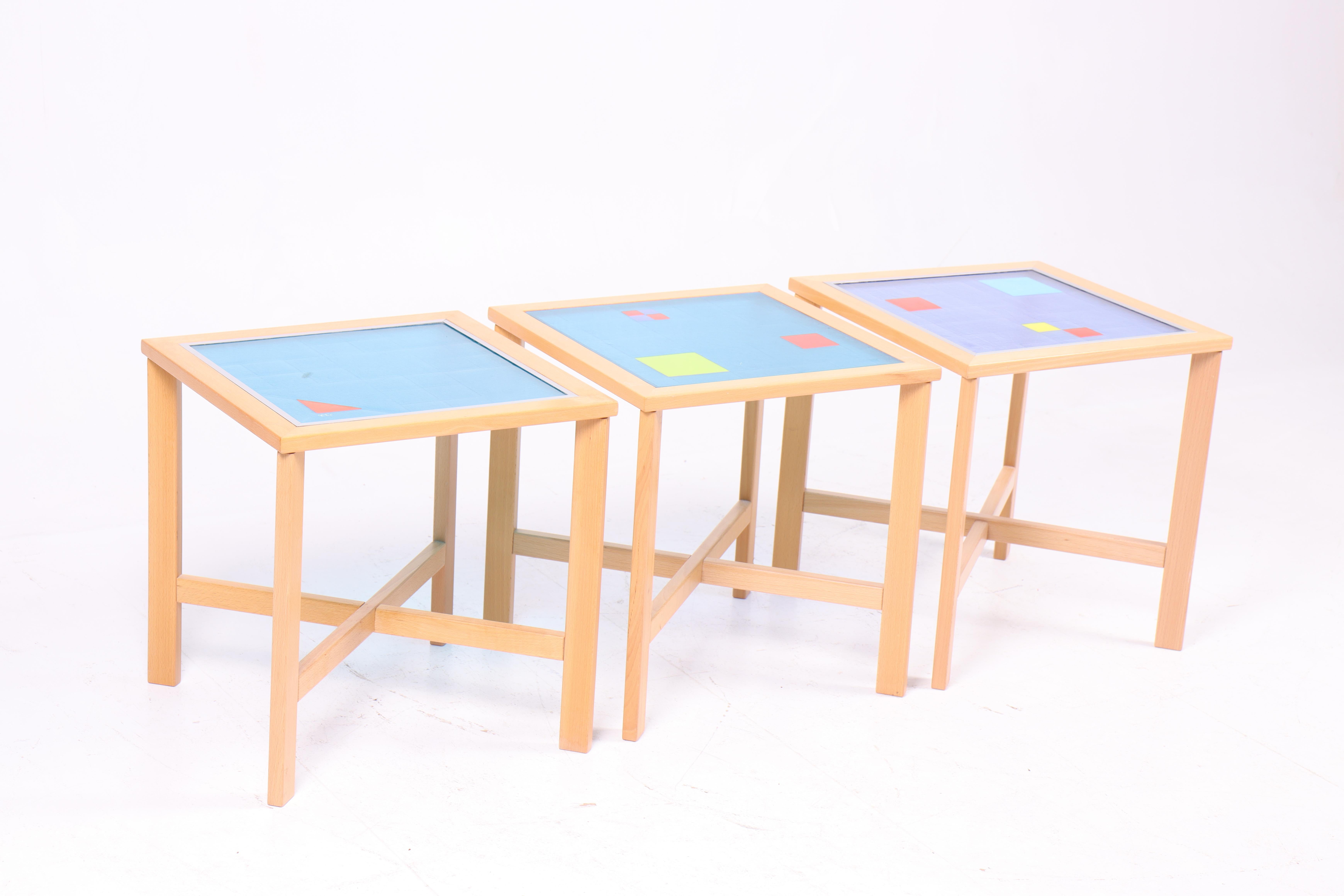 These three lamp tables were produced in the 1990s and are made of beech wood with glass tops created by a Danish glass artist. The tables feature a simple and elegant design with clean lines, characteristic of Danish furniture craftsmanship.

Each