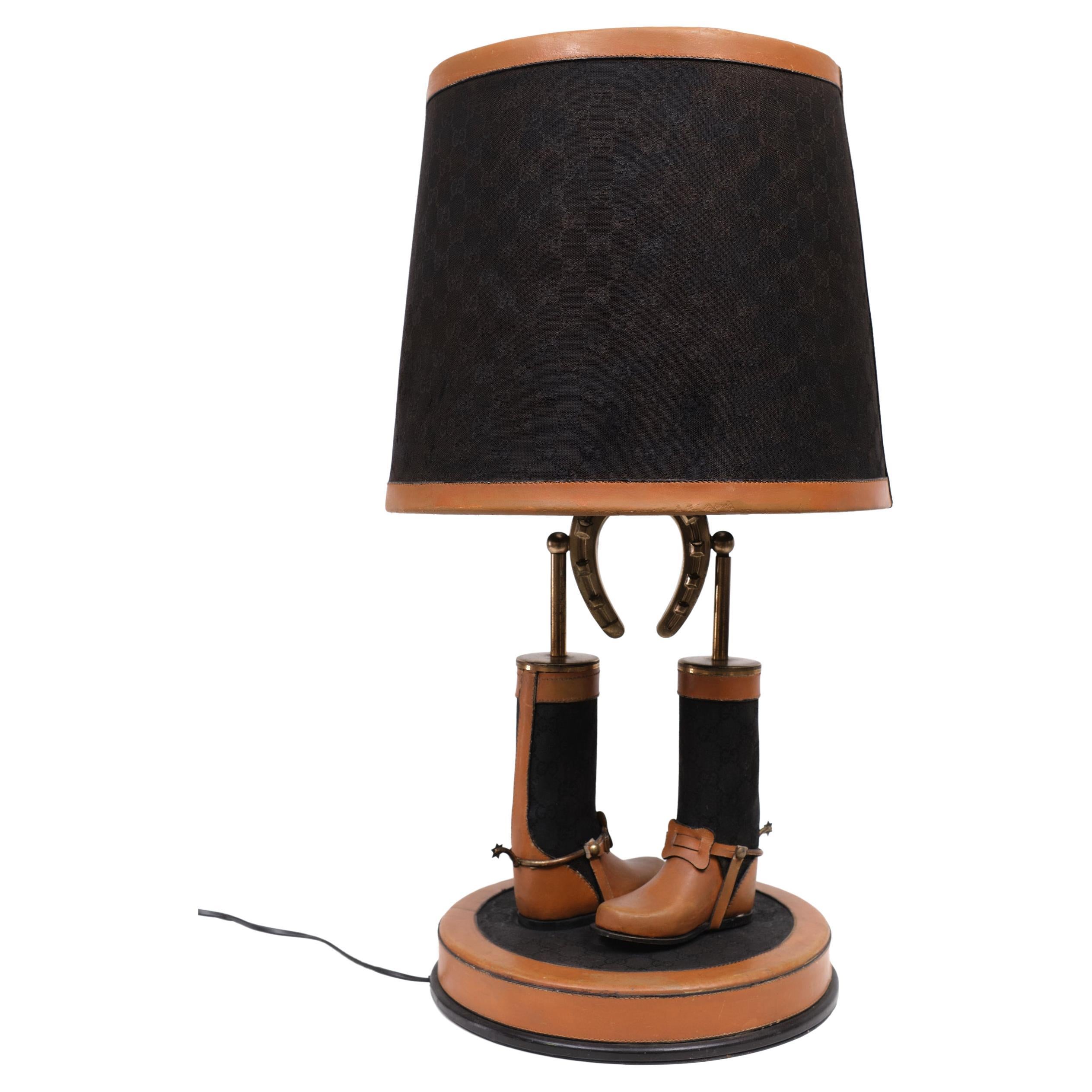 Unique and exclusive table lamp by Gucci Italy with boots and horseshoe and with stirrups.
Metal, leather, webbing and Gucci monogrammed fabric. These lamps were possibly not for retail but part of the display in the Gucci Stores.
There is one