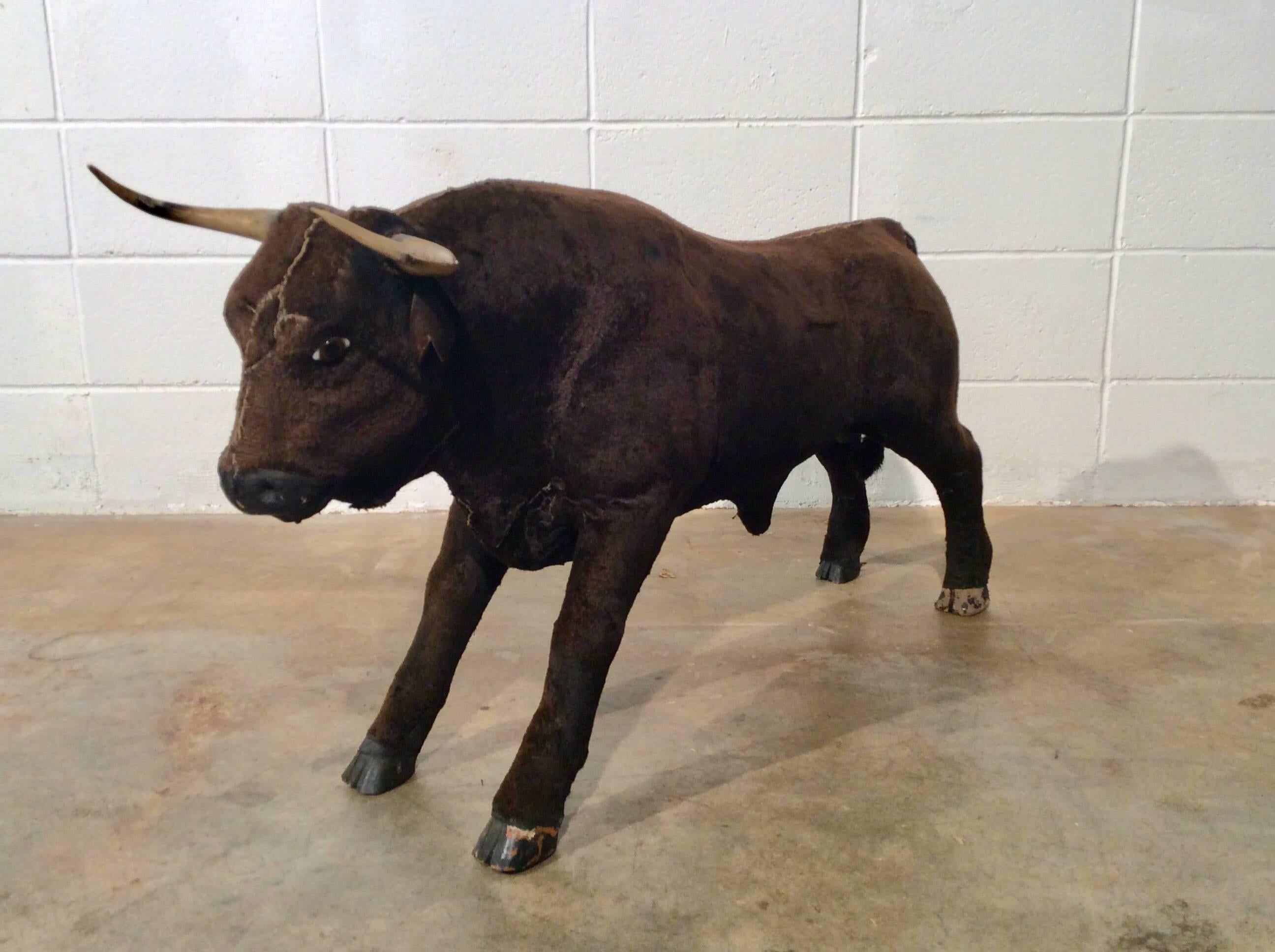 Very unique and quirky pair of handmade Folk Art bull sculptures. The bulls are very realistic and are anatomically correct. They feature glass eyes, plastic horns, wooden feet and nose, all wrapped in what seems to be a flannel material that looks