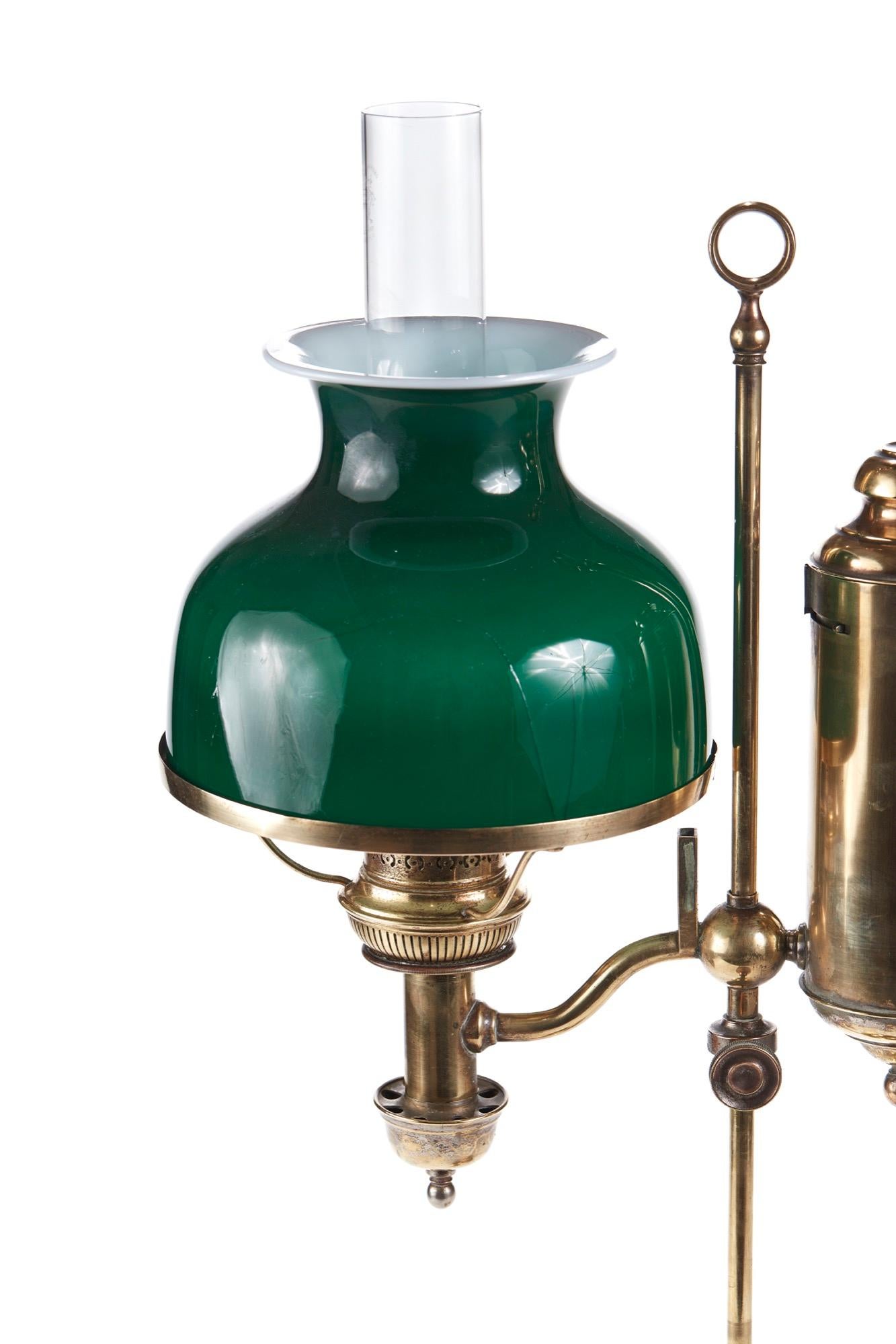 This is a unique 19th century antique adjustable brass desk lamp which has an opalescent green glass shade. Brass oil cylinder, column support on circular base. Lovely condition.