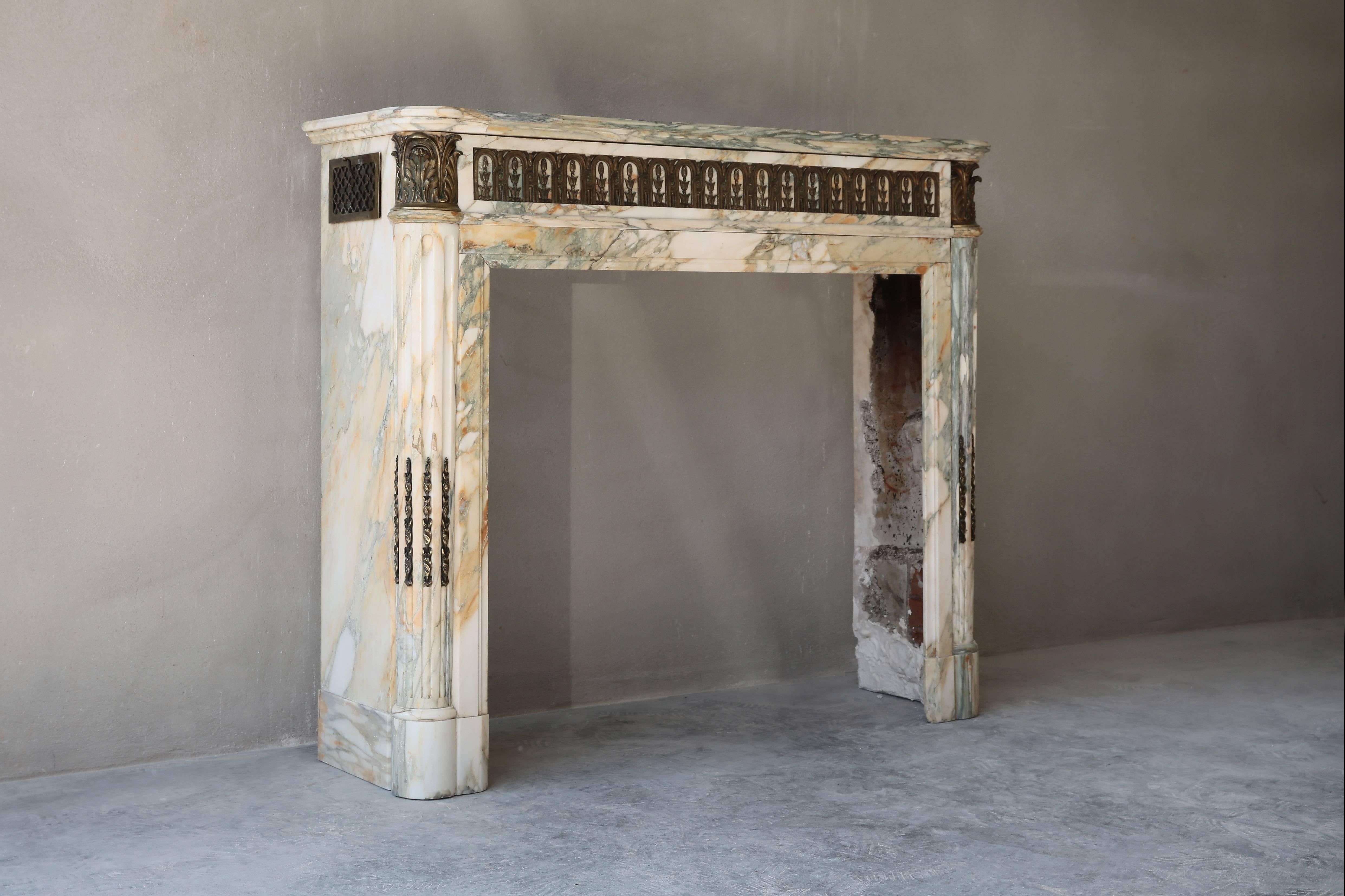 This special and unique antique marble fireplace comes from Paris and dates back to the 19th century. In the time of Louis XVI these chimneys were common. The mantelpiece is richly decorated with ornaments and gilded bronze decorations in the fringe