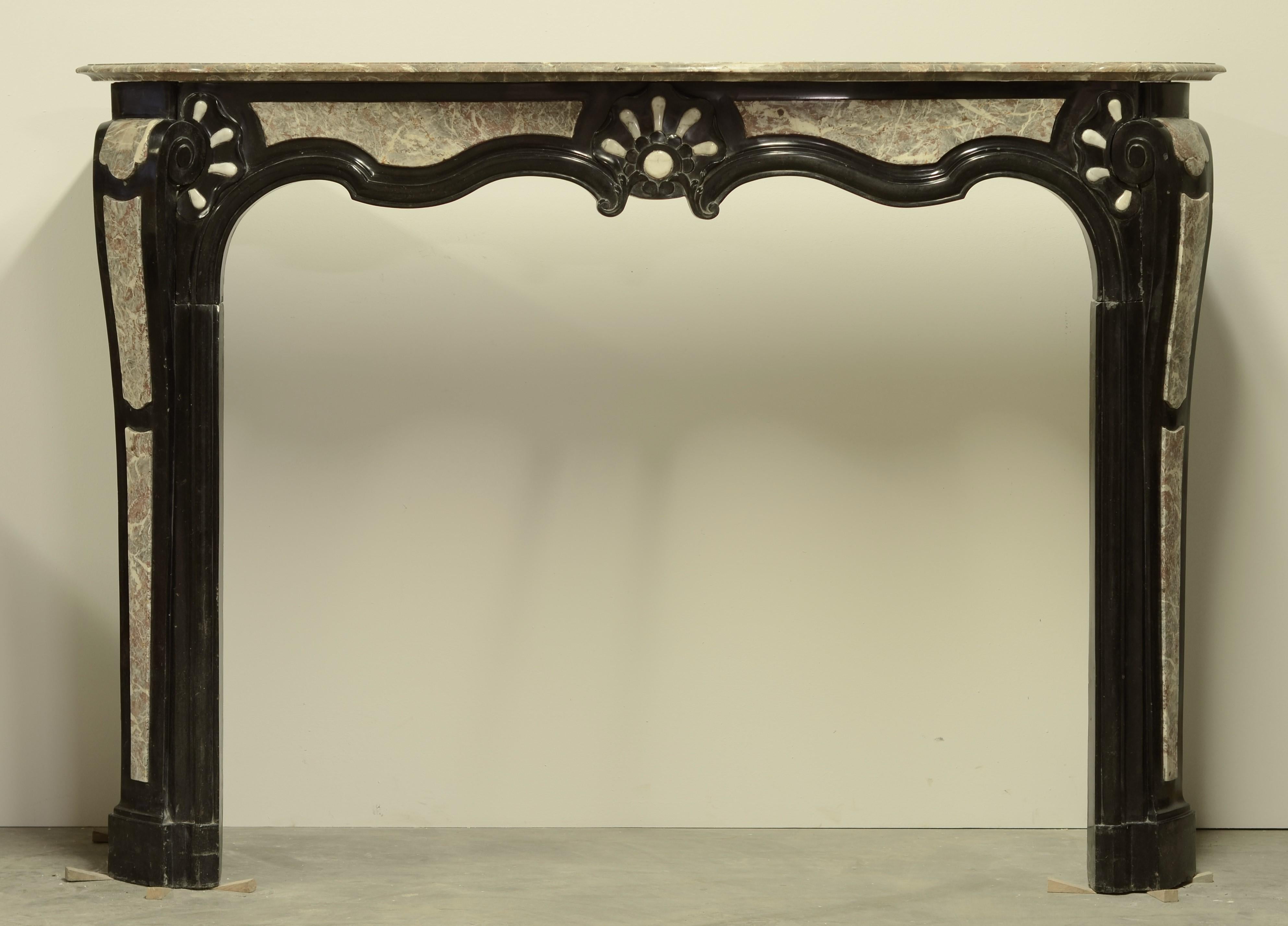 This rare, large 18th century Louis XIV mantelpiece from Leuven (Belgium) is realized in three different types of marble:

Noir de Mazy - The black marble from Belgium.
Rouge Royal - Belgian red marble.
White Carrara marble from