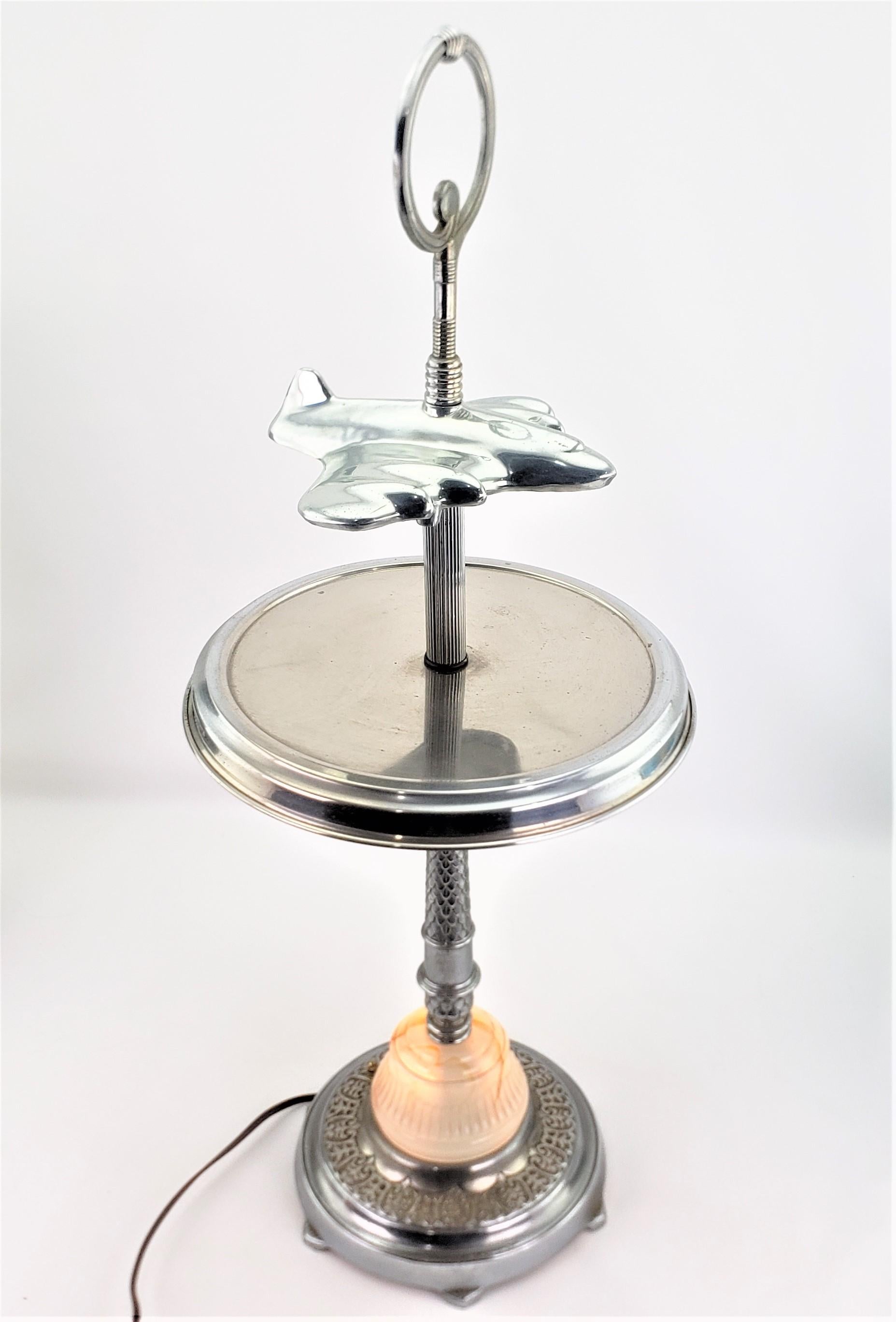 This very unique lighted smoker's stand is unsigned, but presumed to have been made in North America, likely the United States, in approximately 1950 in an Art Deco style. This smoker's stand is done in chromed metal with a streamlined and stylized